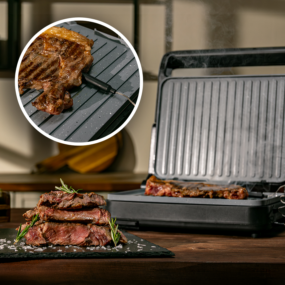 Un bistec a la parrilla apilado. Un termómetro de carne insertado en un bistec.