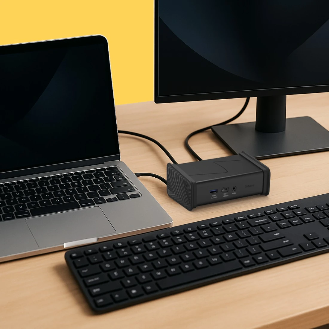 Un ordinateur portable, une station d'accueil, un clavier et un moniteur sur un bureau en bois.