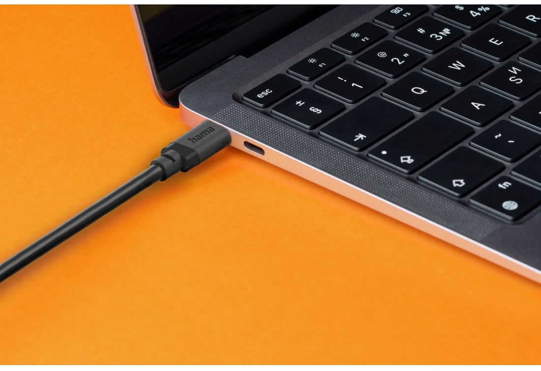 Ein schwarzes USB-C-Kabel wird in einen Laptop gesteckt. Hintergrund orange.