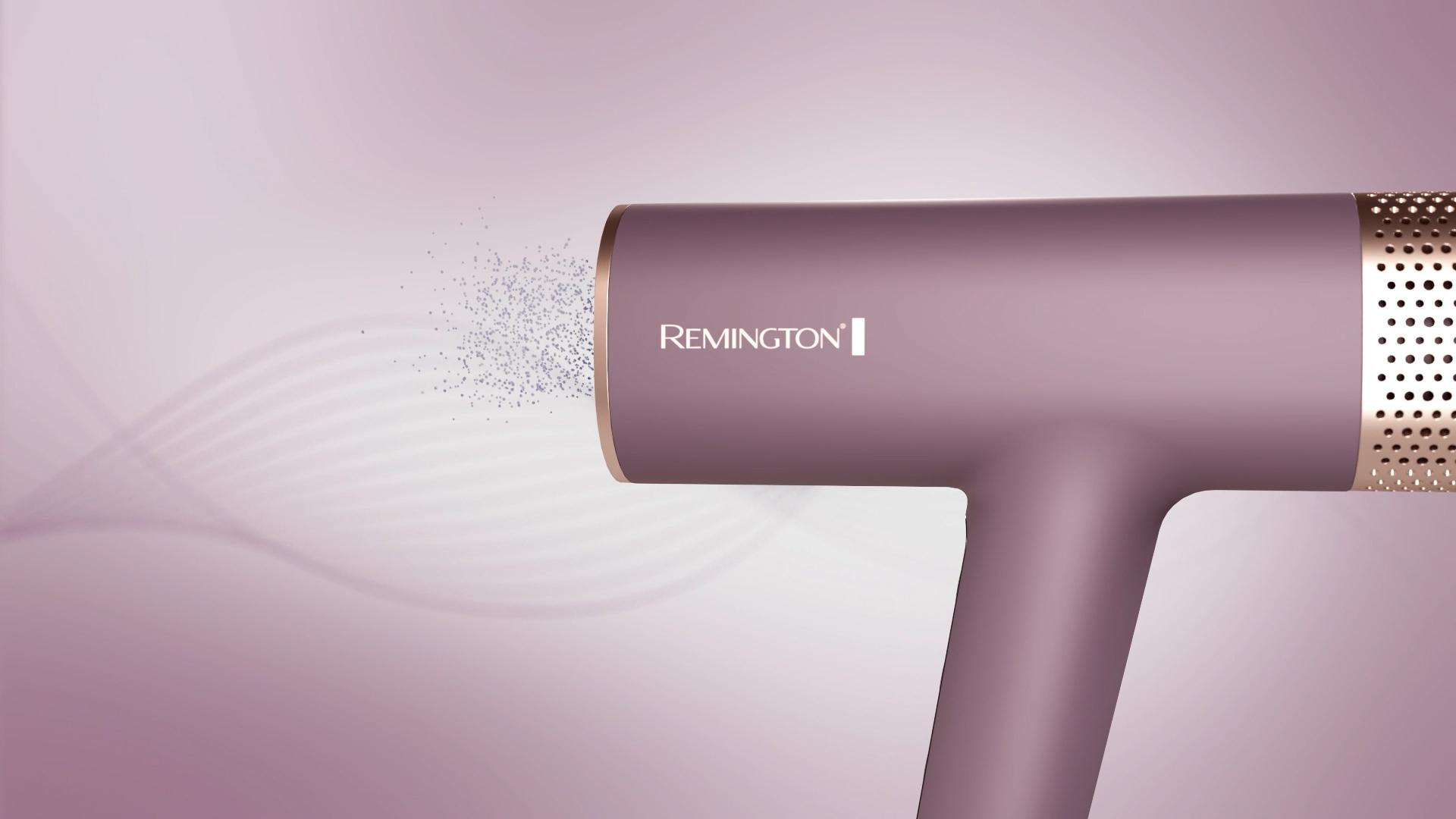 Ein matter, rosafarbener Remington-Haartrockner sprüht winzige Partikel auf einem fliederfarbenen Hintergrund.