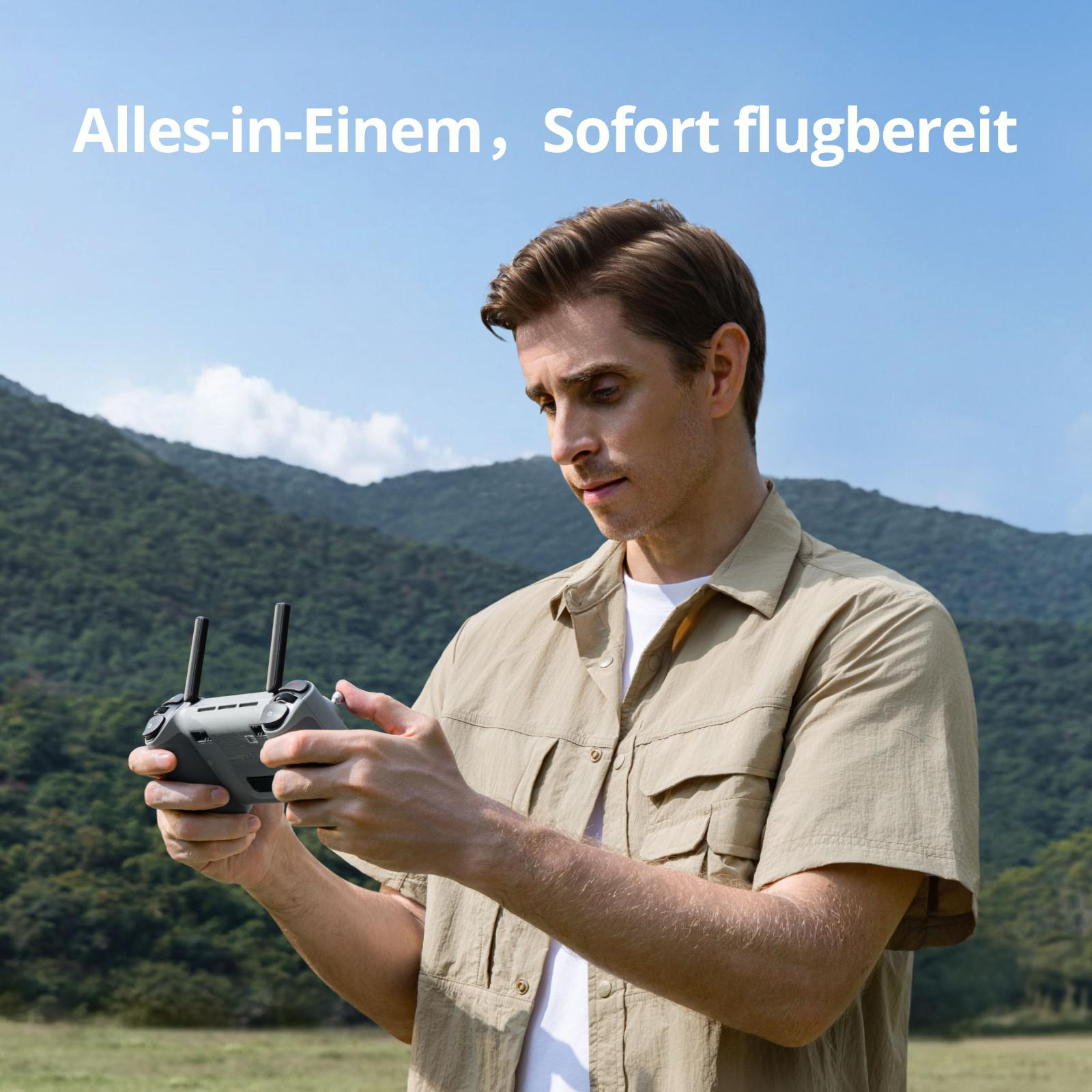 Mann hält Drohnensteuerung im Freien, Berge im Hintergrund.