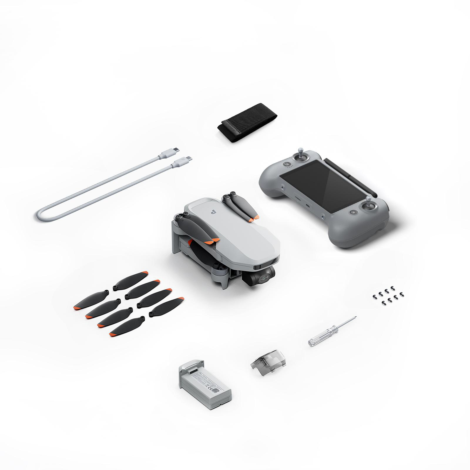 Drohne, Fernbedienung, Ersatzpropeller, Akku und Kabel auf weißem Hintergrund.