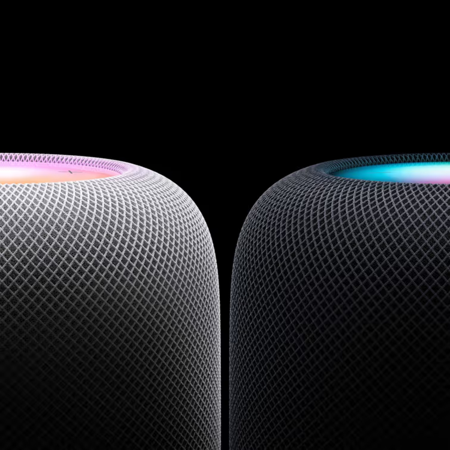 Two grey speakers with illuminated tops against a black background.