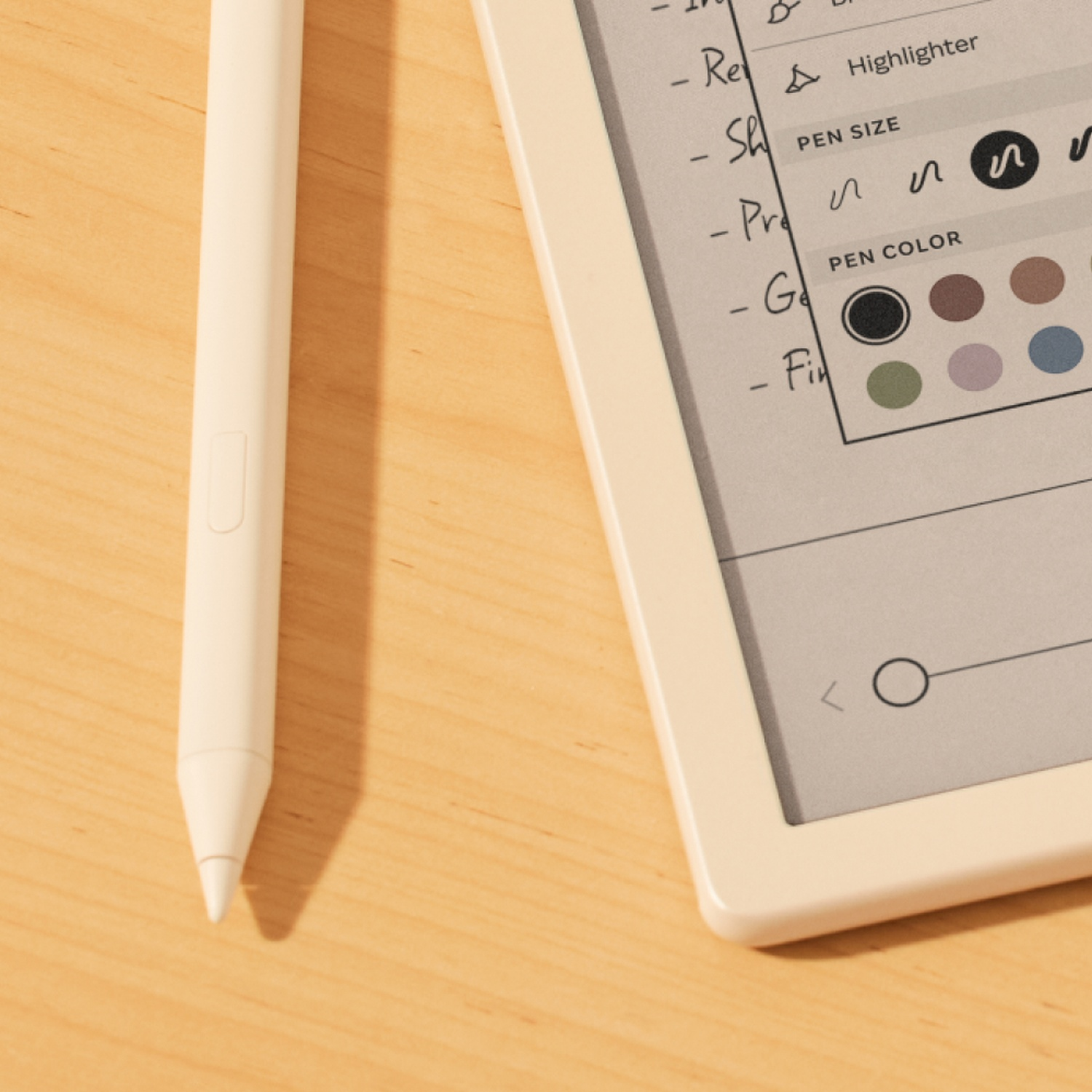 Un stylet blanc repose à côté d'une tablette affichant une application de notes avec des options de stylet.