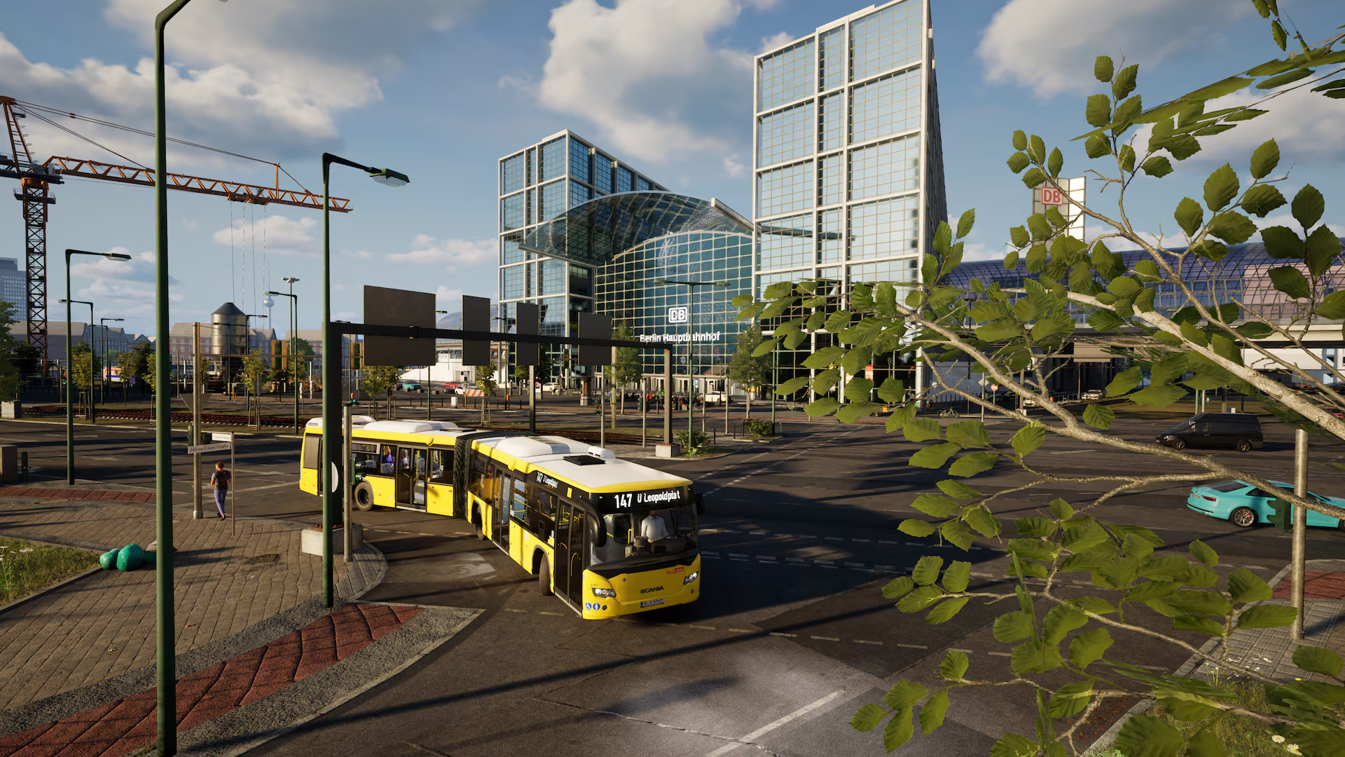 Un bus articulé jaune passe devant des immeubles modernes en verre.