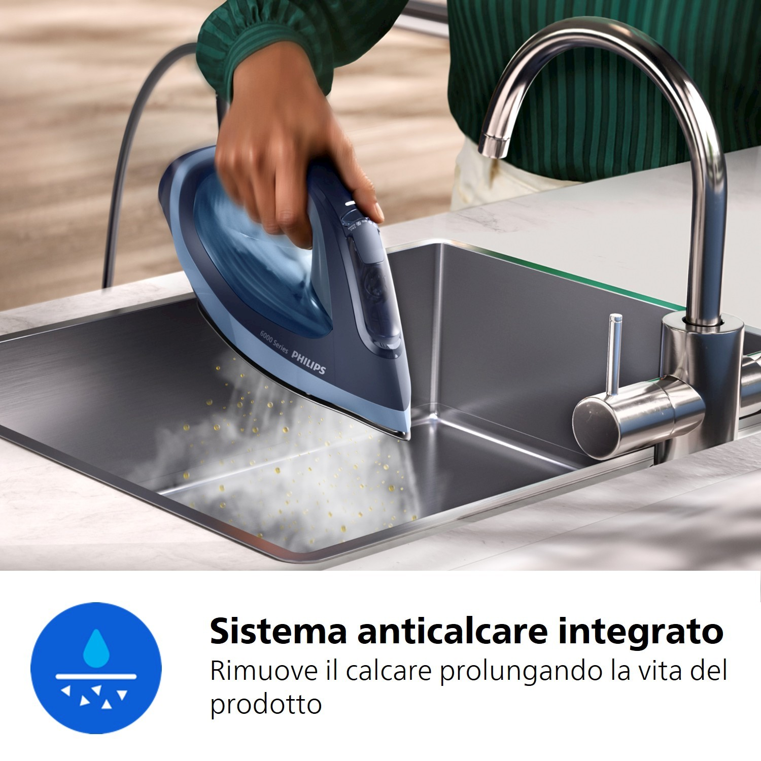 Una mano tiene un ferro Philips blu sopra un lavello, sale vapore.