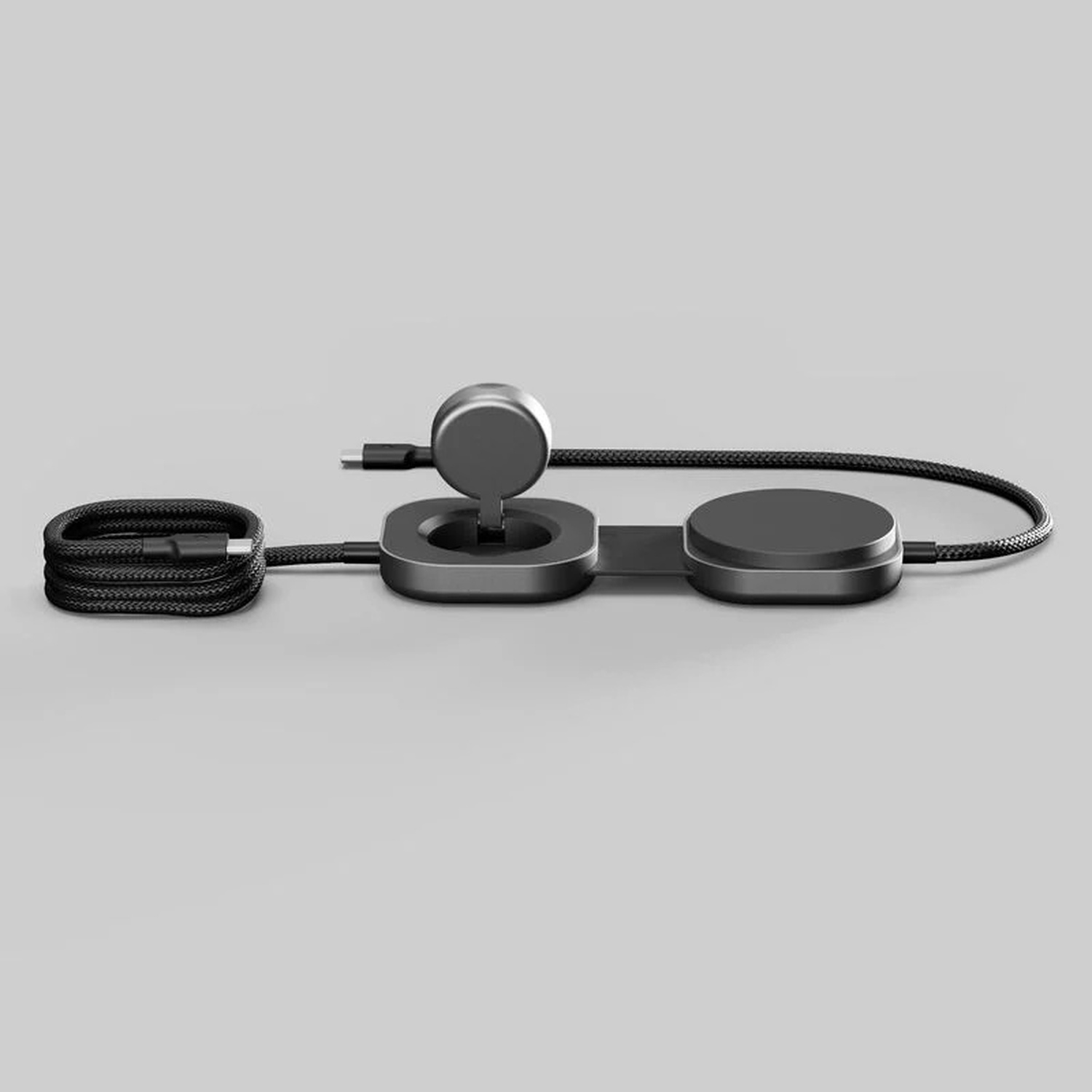 Un cavo di ricarica nero arrotolato accanto a un caricabatterie con due pad rotondi e un supporto.
