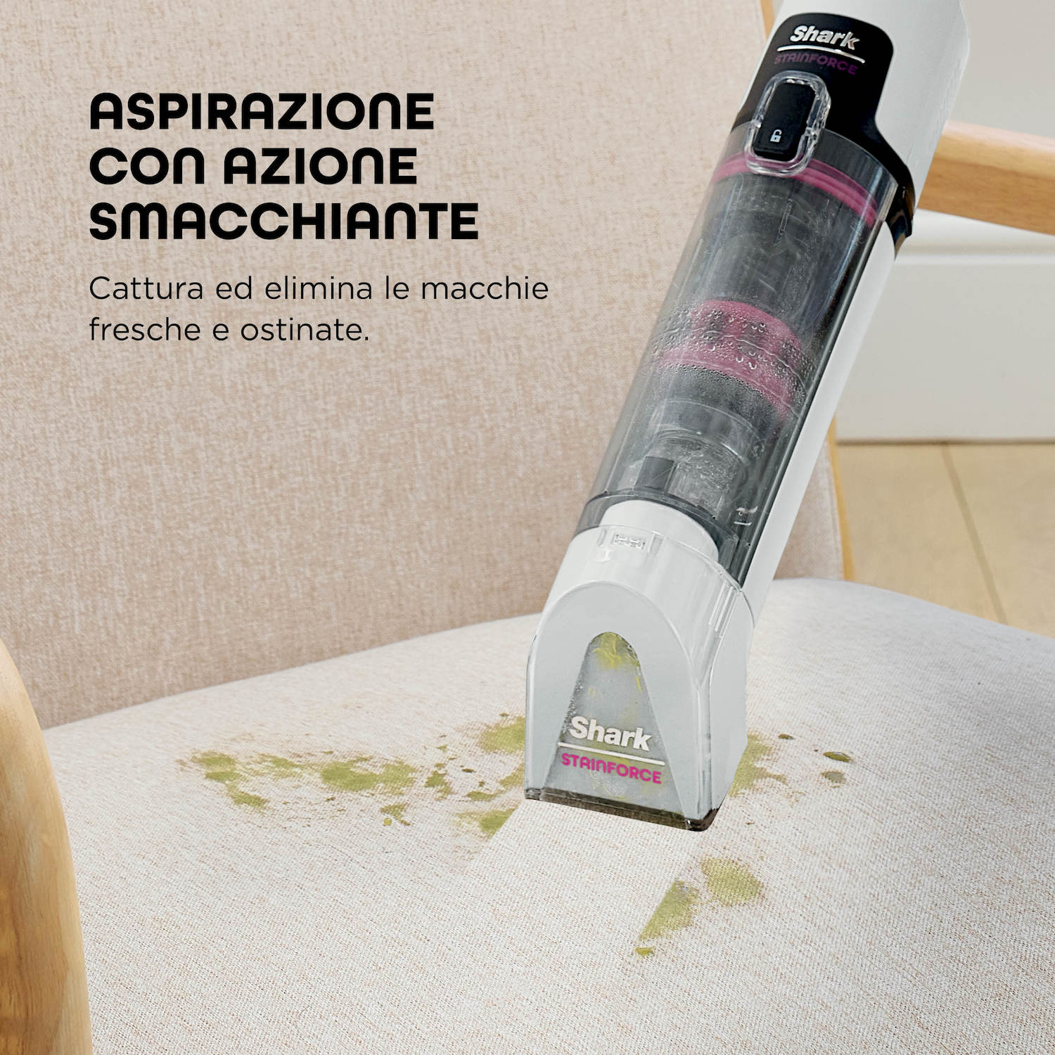 Un aspirapolvere portatile pulisce macchie verdi su una sedia di tessuto.