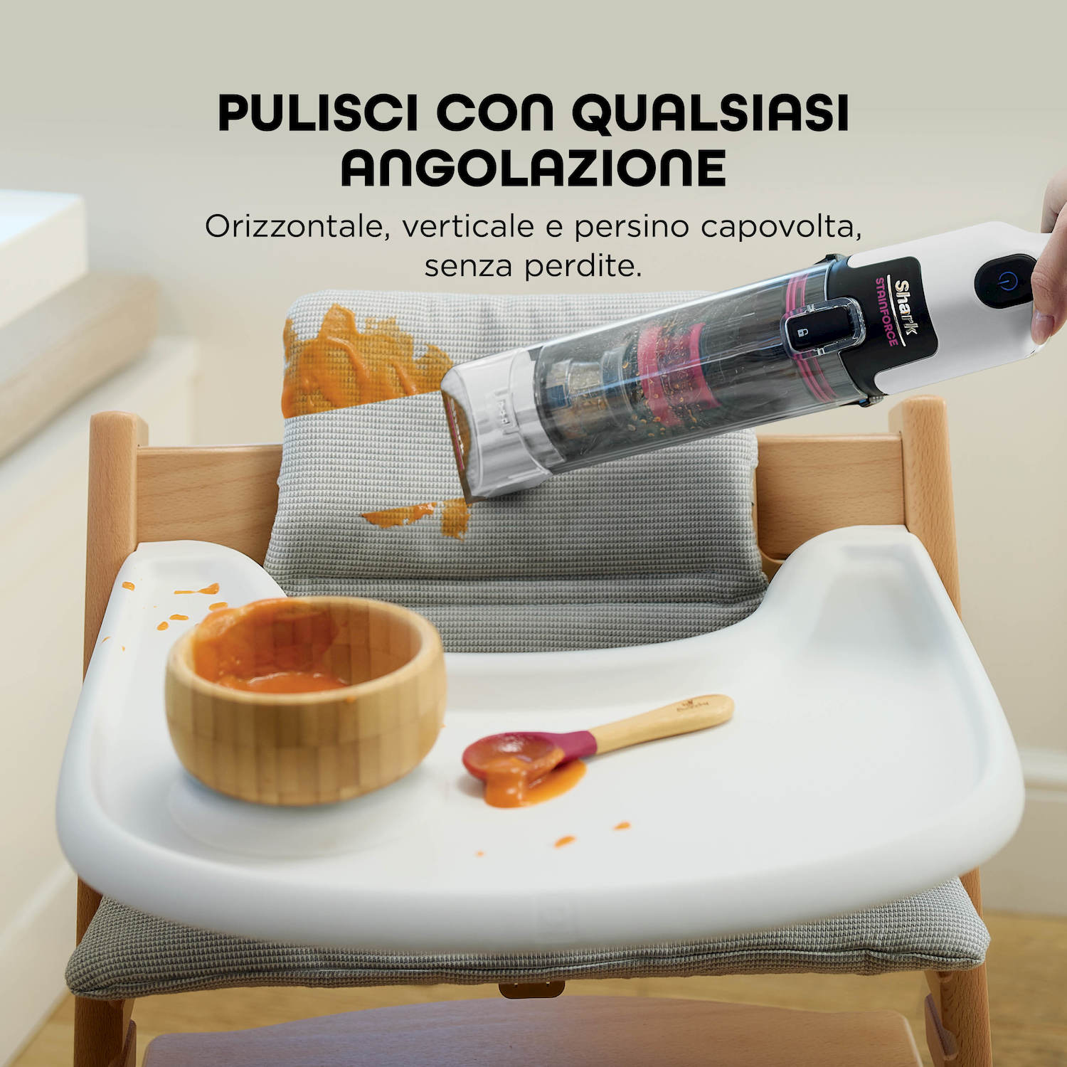 Un aspirapolvere portatile pulisce cibo rovesciato su un seggiolone.