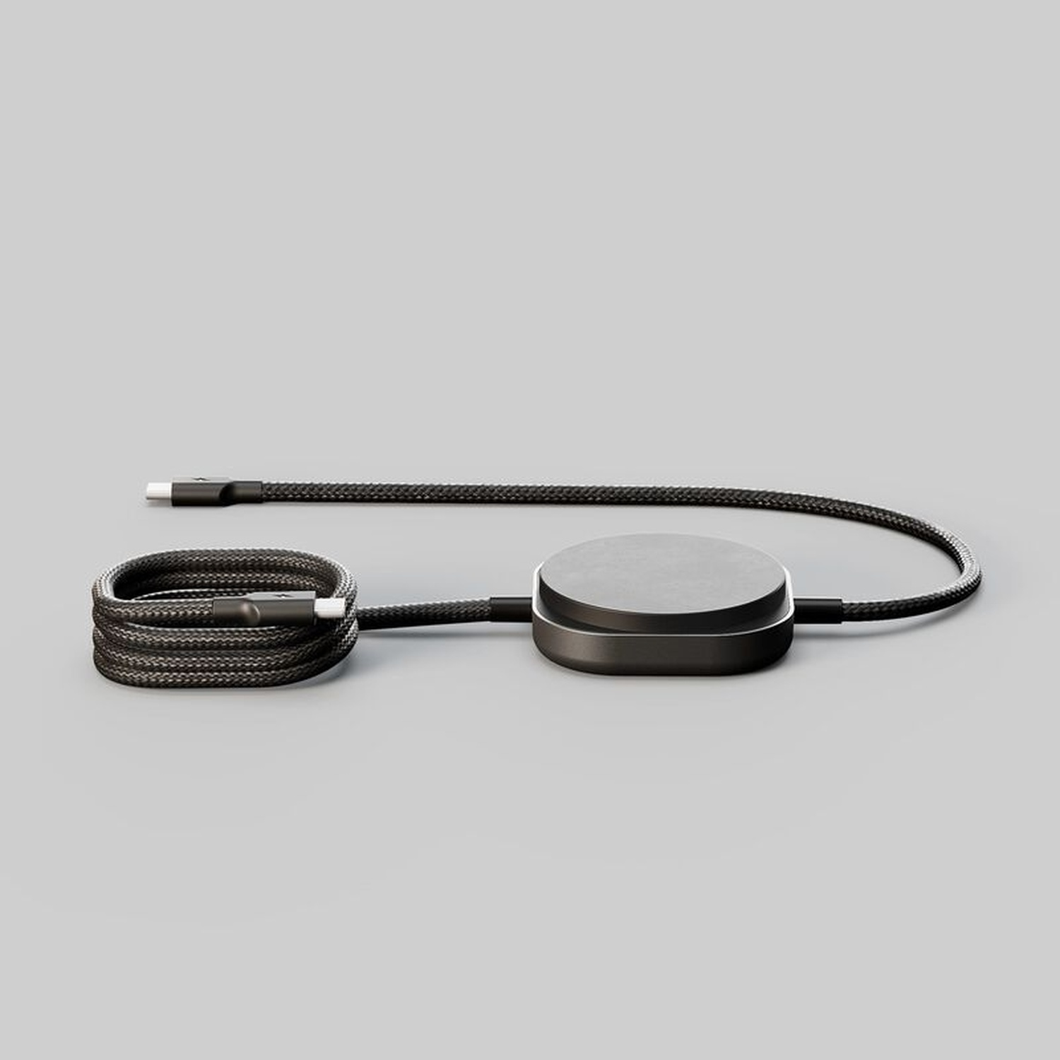 Un cavo di ricarica nero con connettore USB-C è avvolto su sfondo grigio.