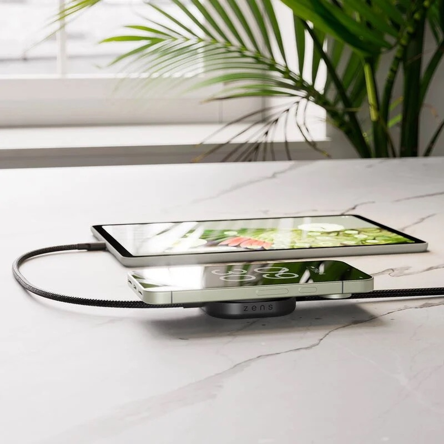 Uno smartphone e un tablet in carica su una superficie di marmo tramite cavo.