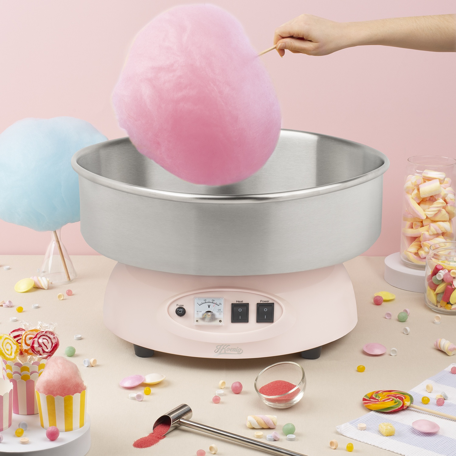 Macchina per zucchero filato rosa con zucchero filato blu e rosa. Caramelle circondano la macchina.