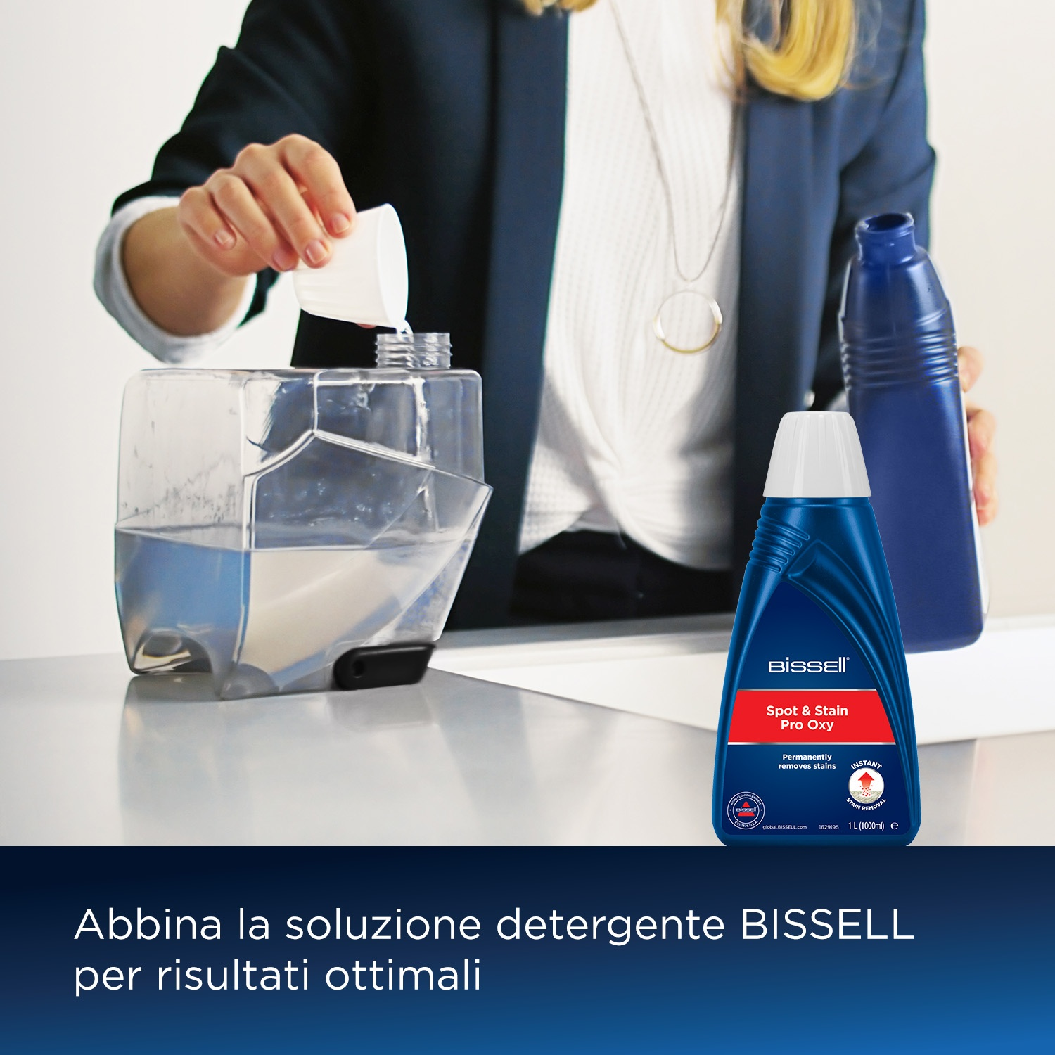 Una persona versa liquido in un serbatoio. Una bottiglia BISSELL Spot & Stain Pro Oxy è vicina.
