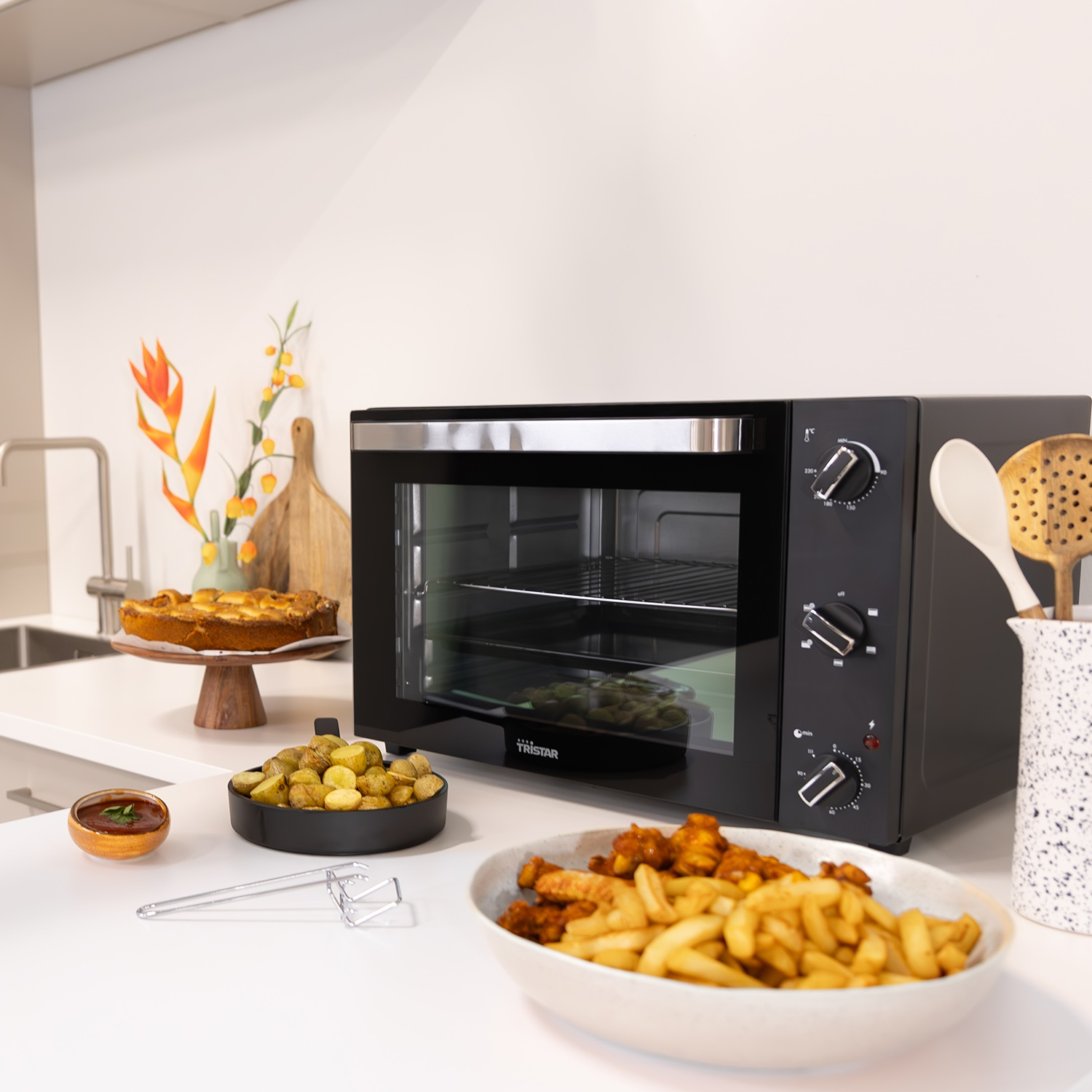 Un forno da banco nero con cibo, tra cui una torta e patatine fritte.