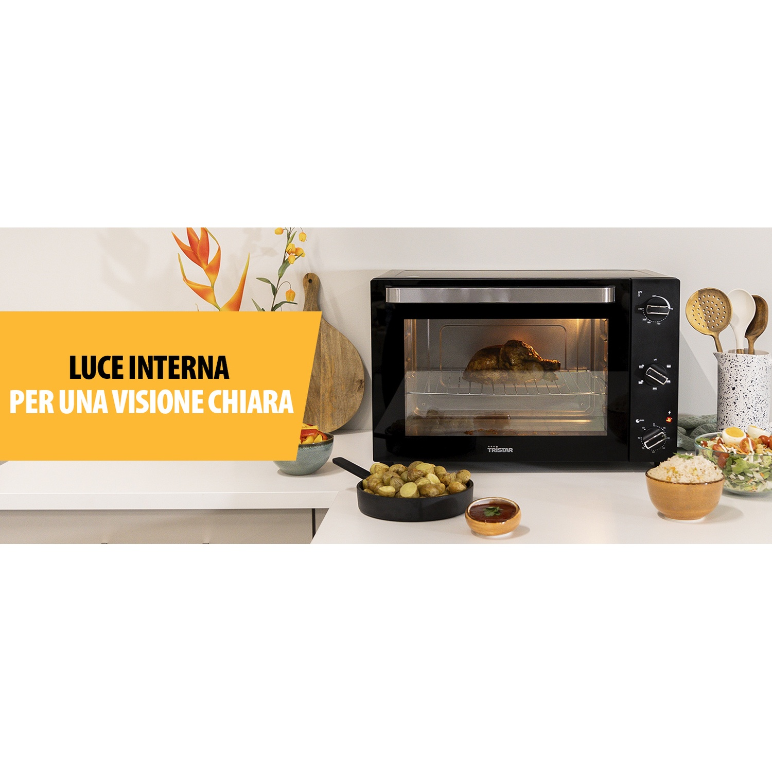 Forno nero con pollo arrosto all'interno, contorni accanto.