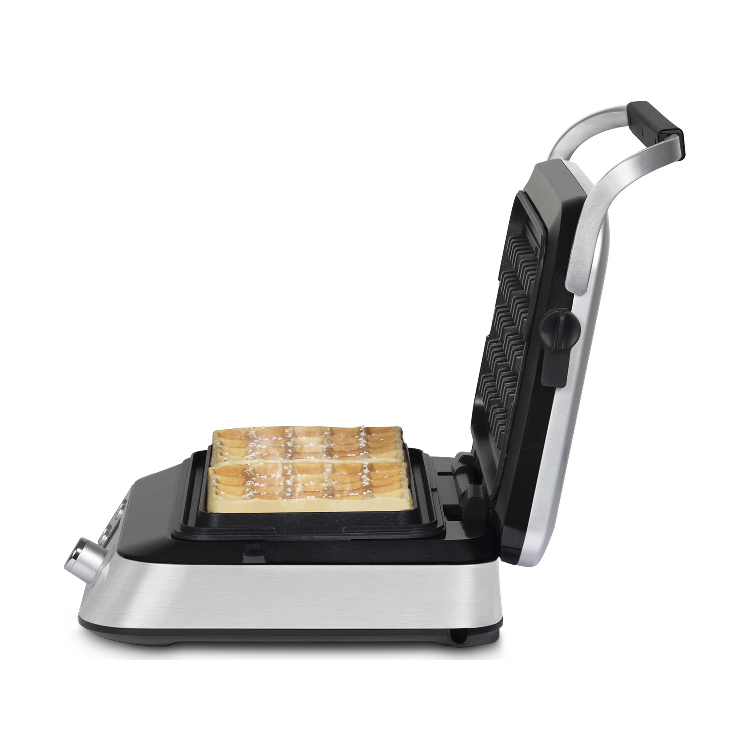 Una piastra per waffle aperta con due waffle spolverati di zucchero a velo.
