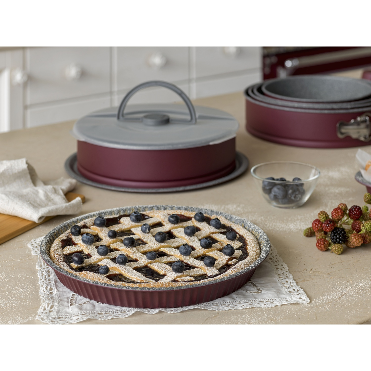 Una crostata di mirtilli a griglia è sul tavolo vicino a teglie.