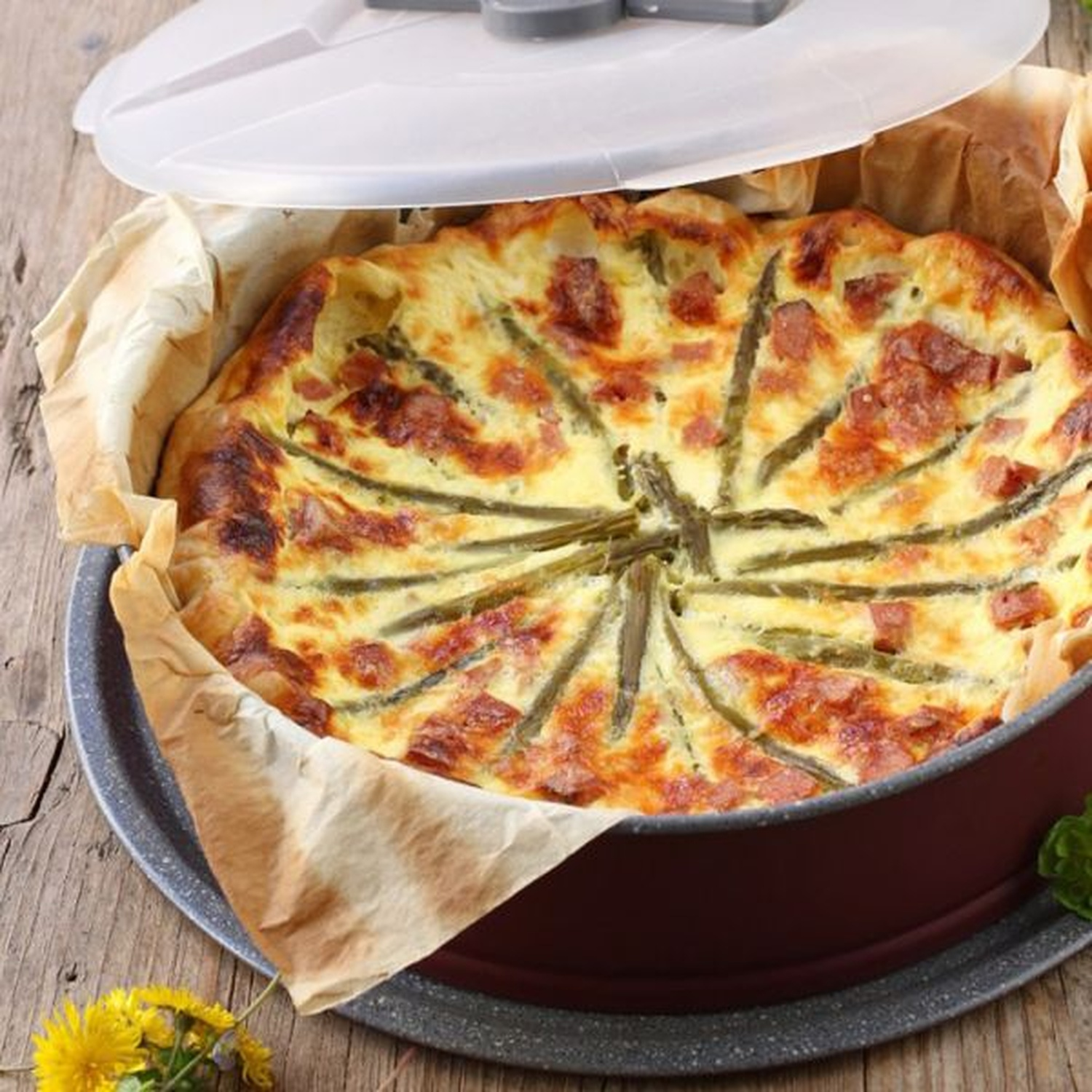 Una torta salata con asparagi e pancetta è servita in una teglia.