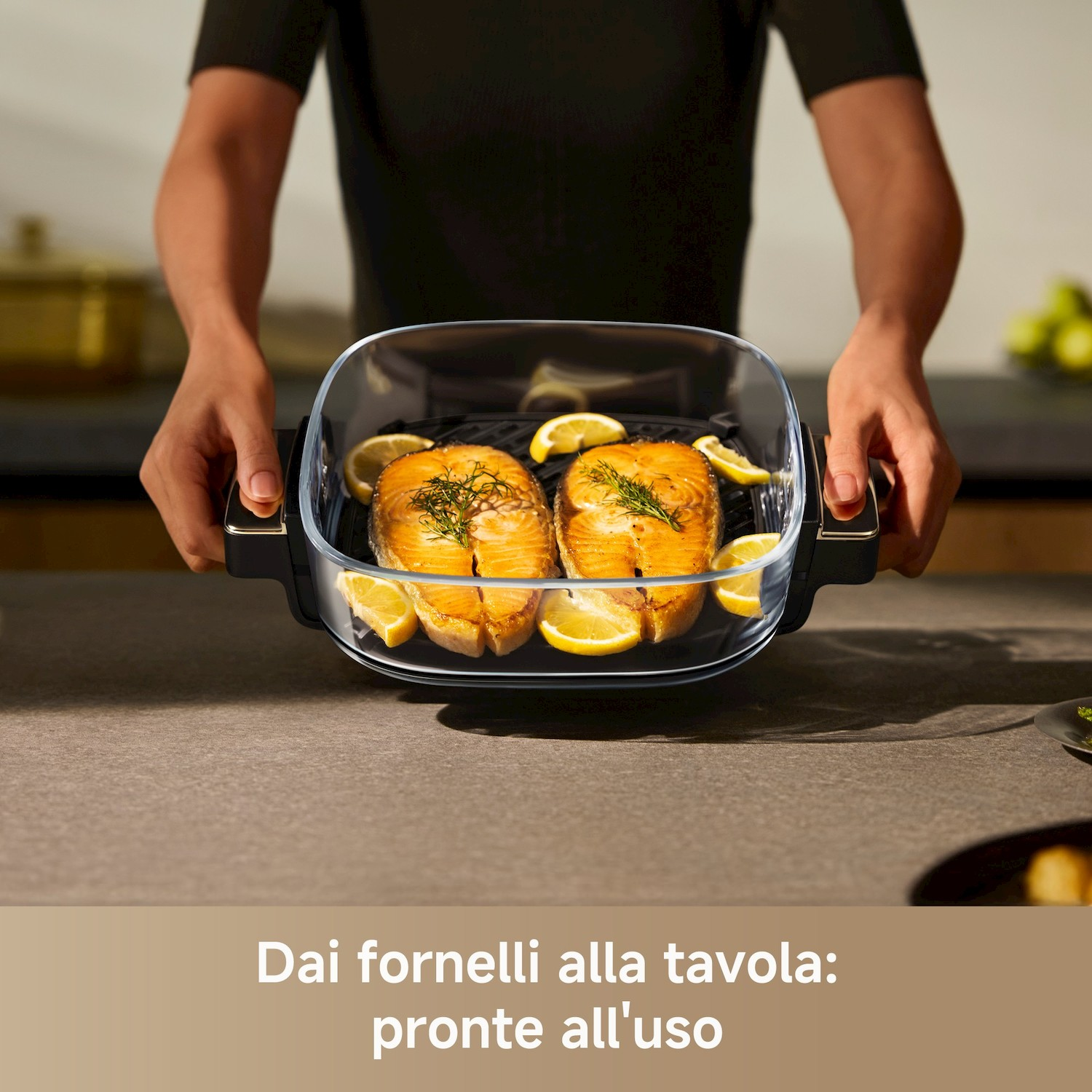 Due filetti di salmone grigliati con limone in una padella di vetro tenuta da una persona.
