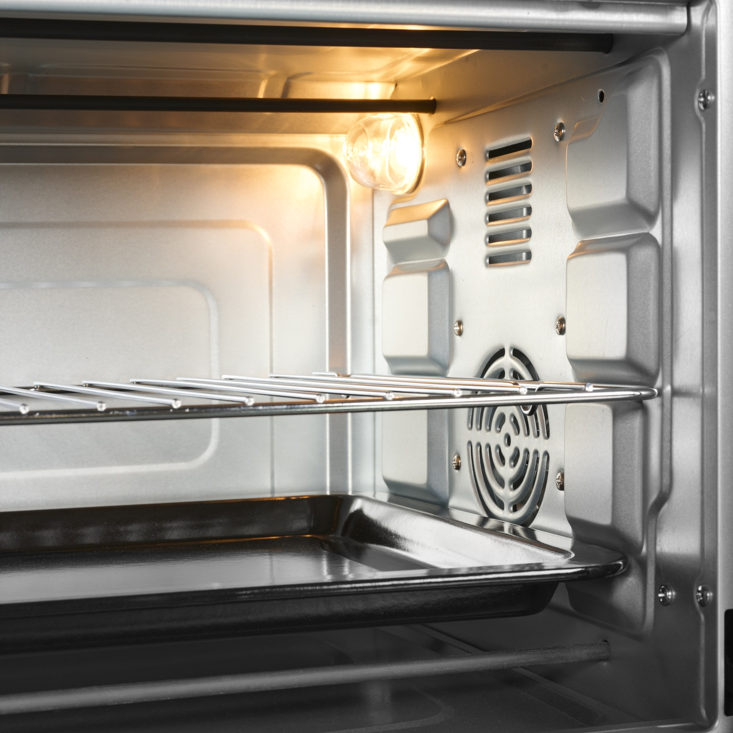 Interno di un forno con griglia e teglia. Una luce è accesa.