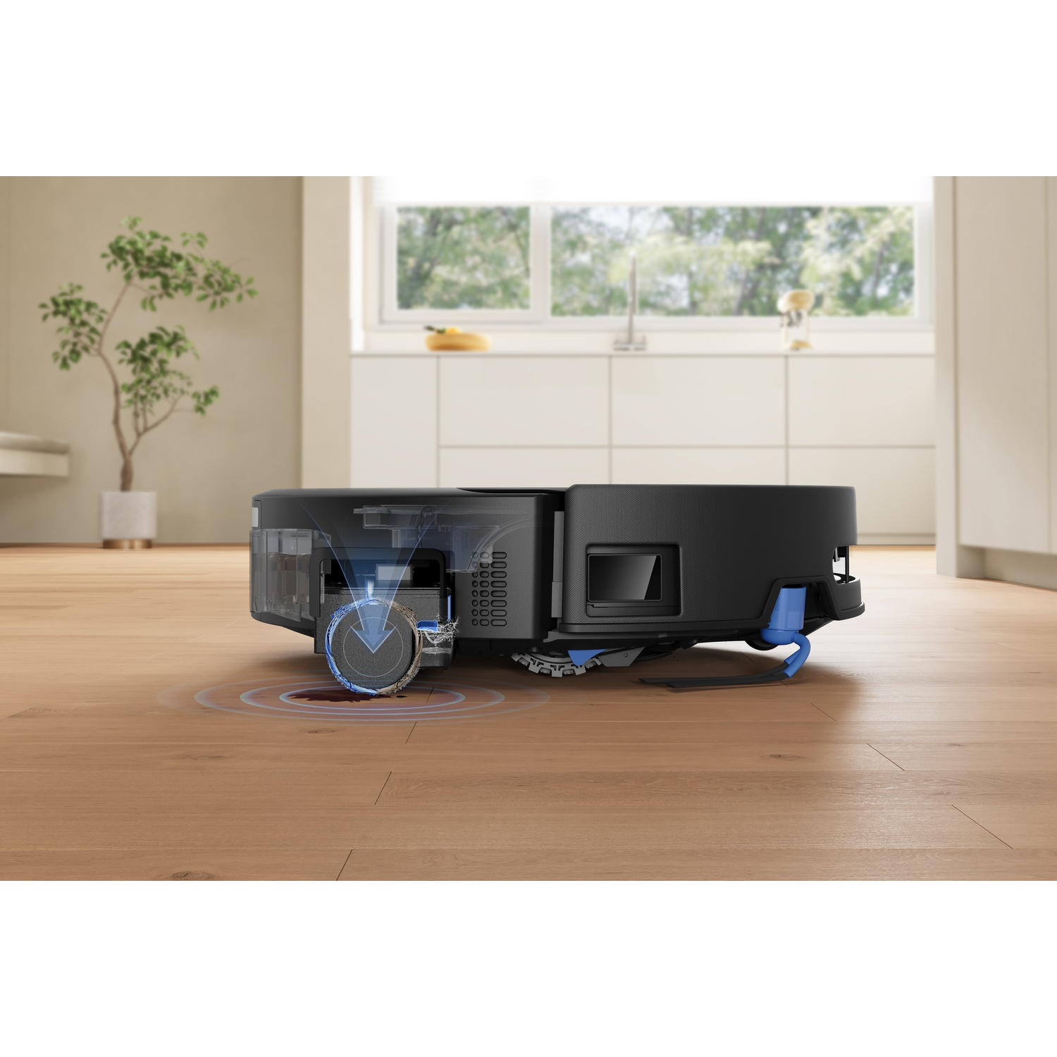 Aspirapolvere robot nero con accenti blu su pavimento in legno, cucina sullo sfondo.