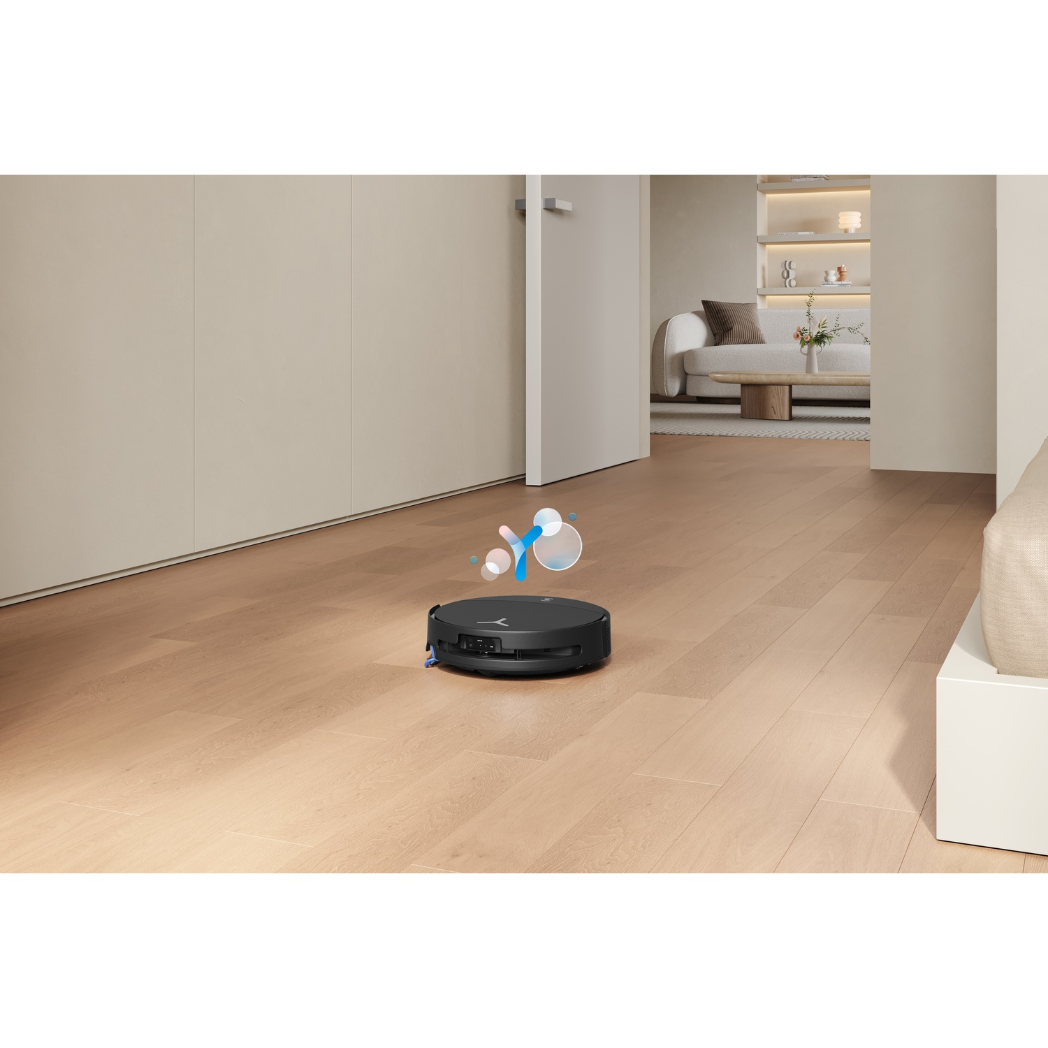 Un robot aspirapolvere nero pulisce un pavimento in legno in un soggiorno moderno.