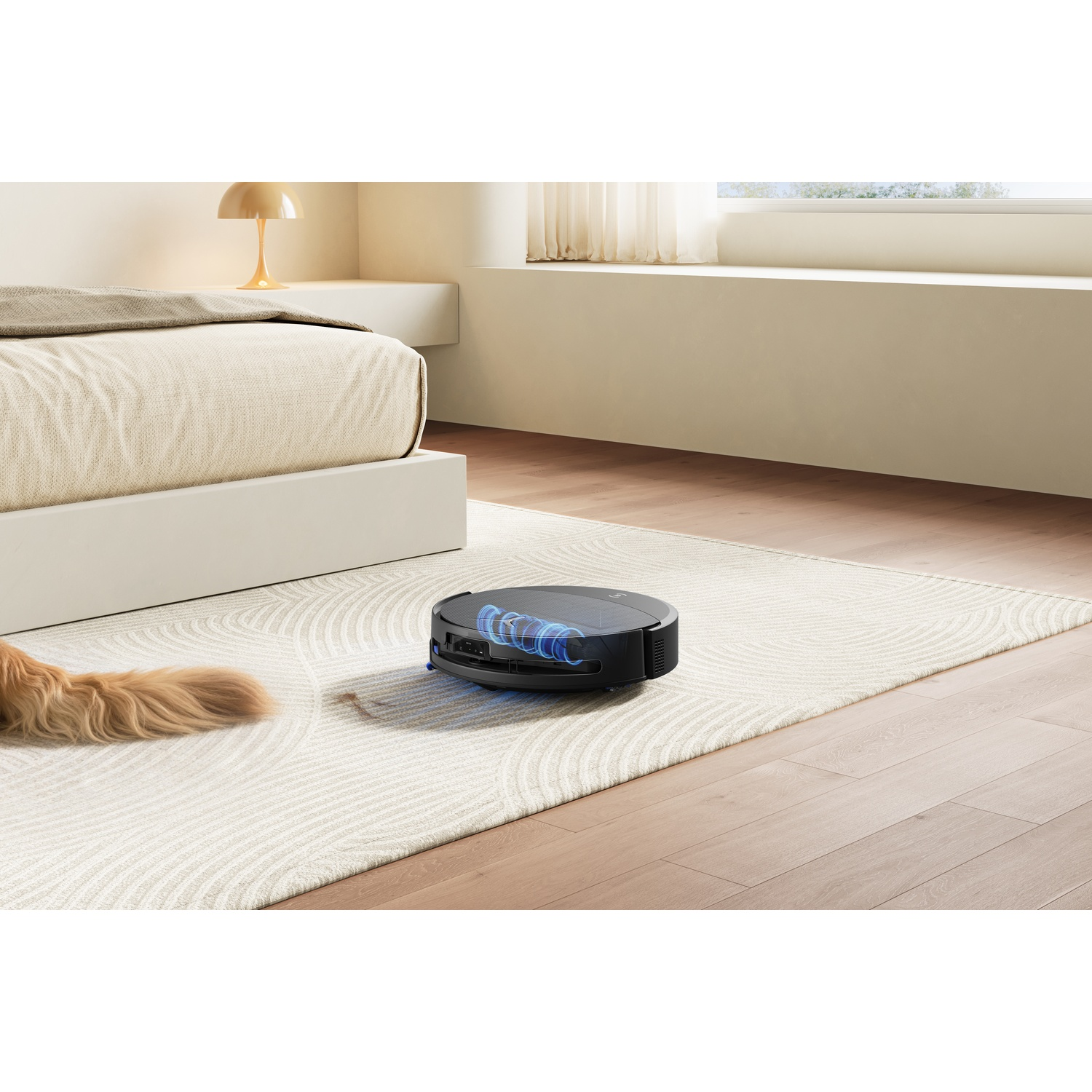 Un robot aspirapolvere rotondo e nero pulisce un tappeto accanto a un letto.