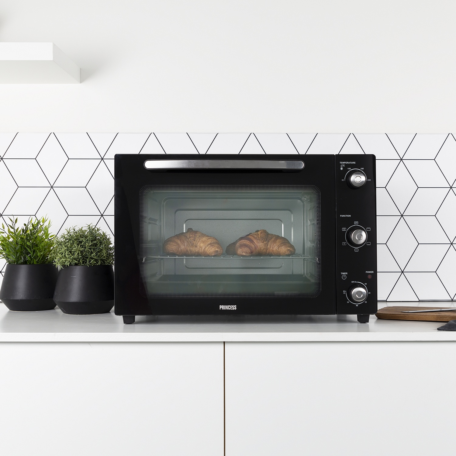 Un forno da banco nero con due croissant sulla griglia.