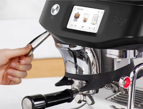 Ręka obsługuje chromowaną dźwignię czarnej ekspresu Sage z ekranem dotykowym.