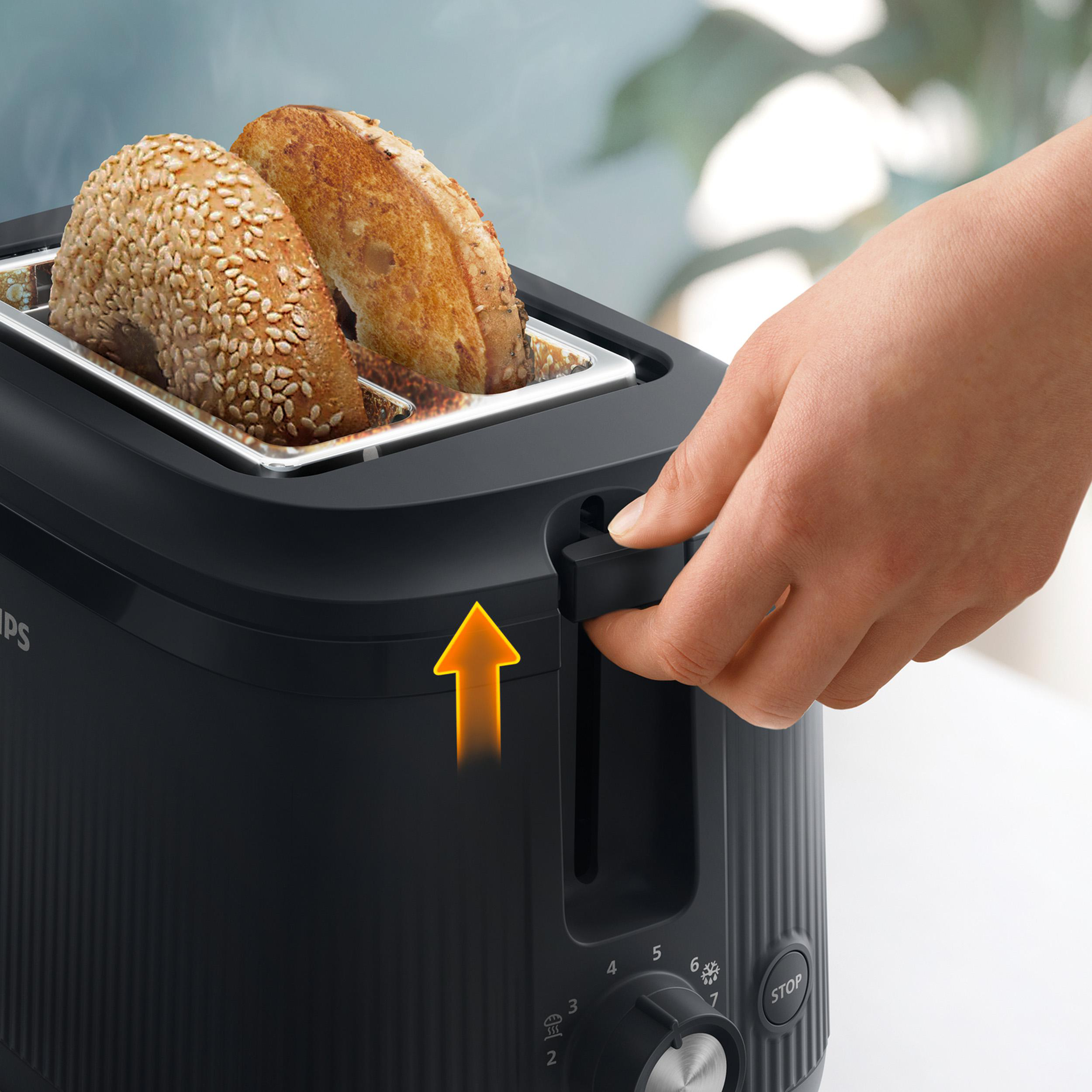 Eine Hand bedient einen Toaster mit zwei Bagels, die toasten.