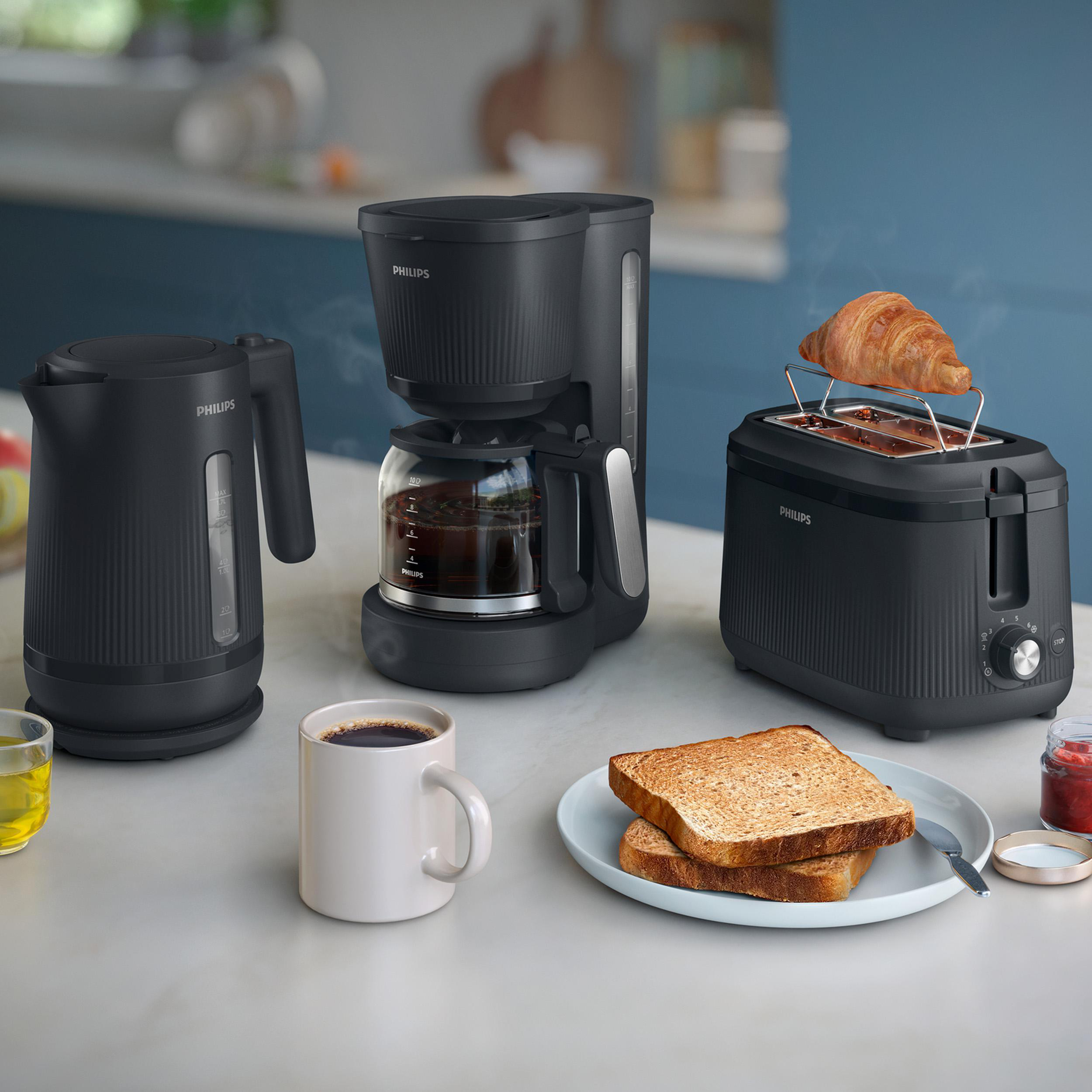 Schwarzer Wasserkocher, Kaffeemaschine und Toaster mit Frühstücksgeschirr.