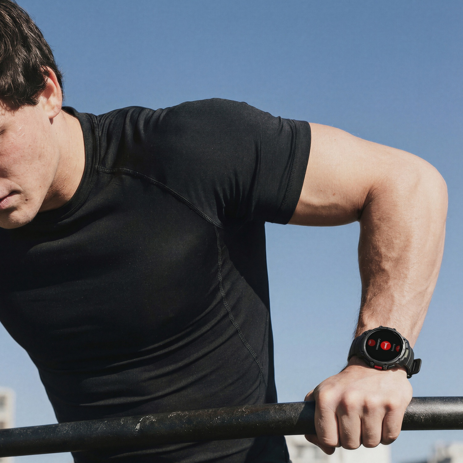 Man in black t-shirt doing dips on a bar, wearing a smartwatch.