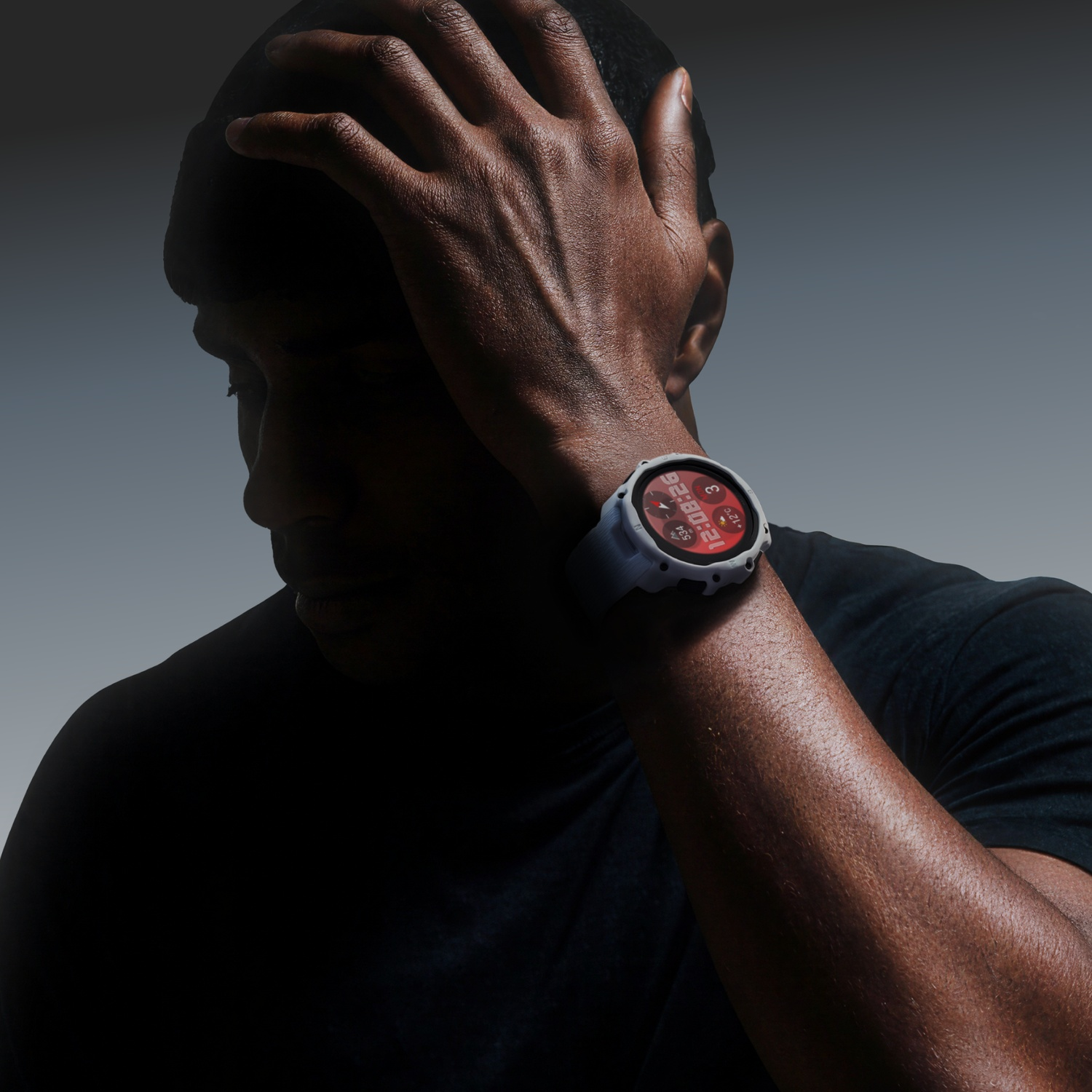 Man with dark skin with hand on head. Light-colored watch on wrist.