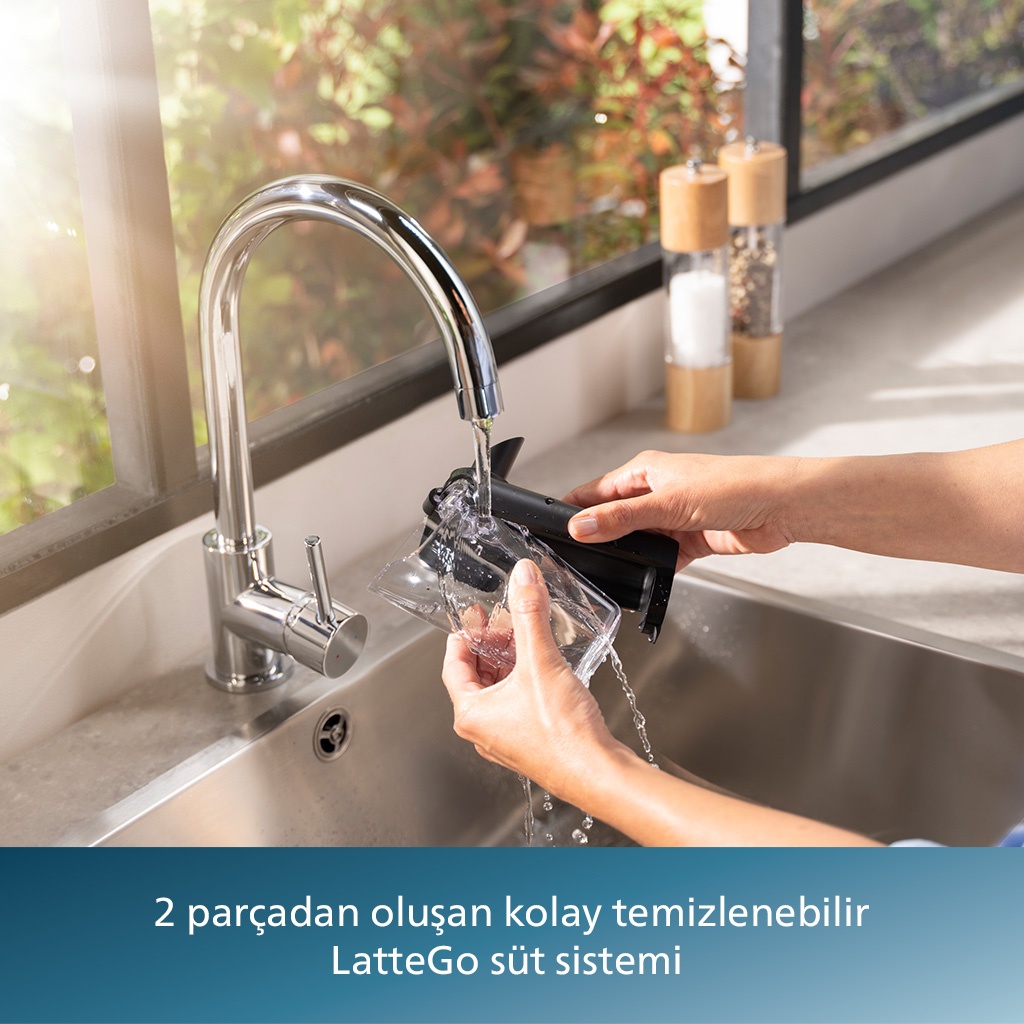 Kişi lavaboda akan su altında süt sistemi parçalarını duruluyor.