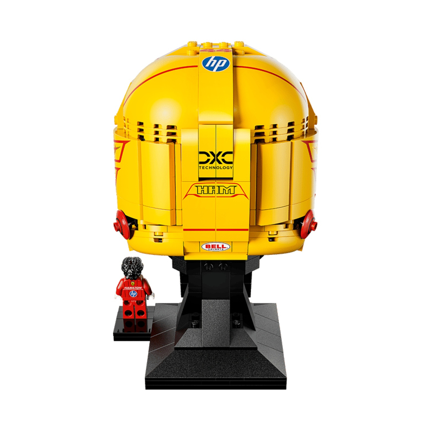 Un casco Lego giallo con accenti rossi si trova su una base nera accanto a una piccola figura Lego.