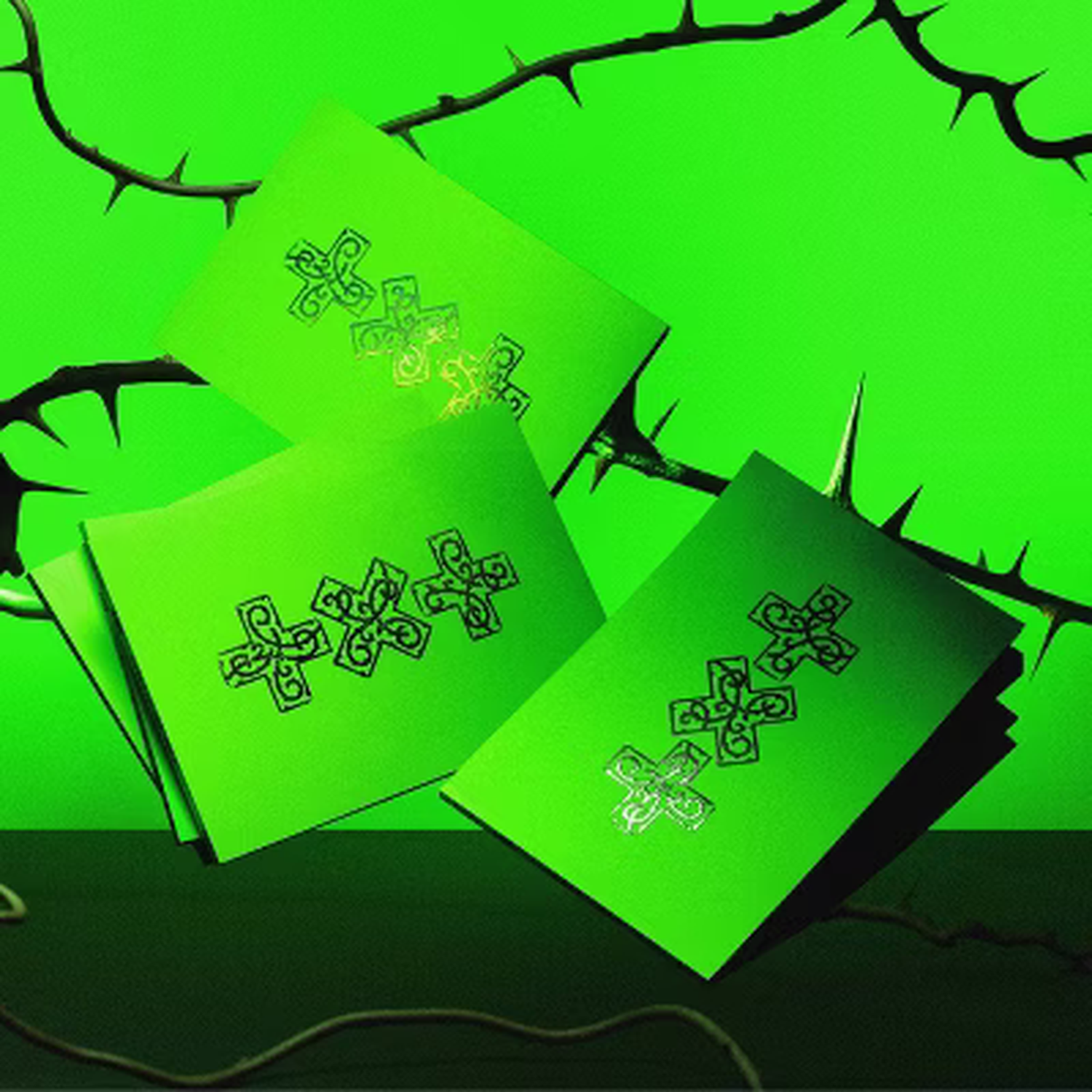 Drie groene kaarten met een XXX-symbool liggen op een groene achtergrond met doornige takken.