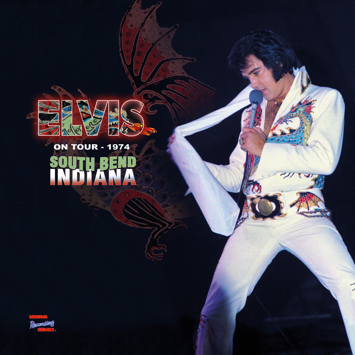 Elvis Presley in a white dragon-embroidered suit, singing on stage.