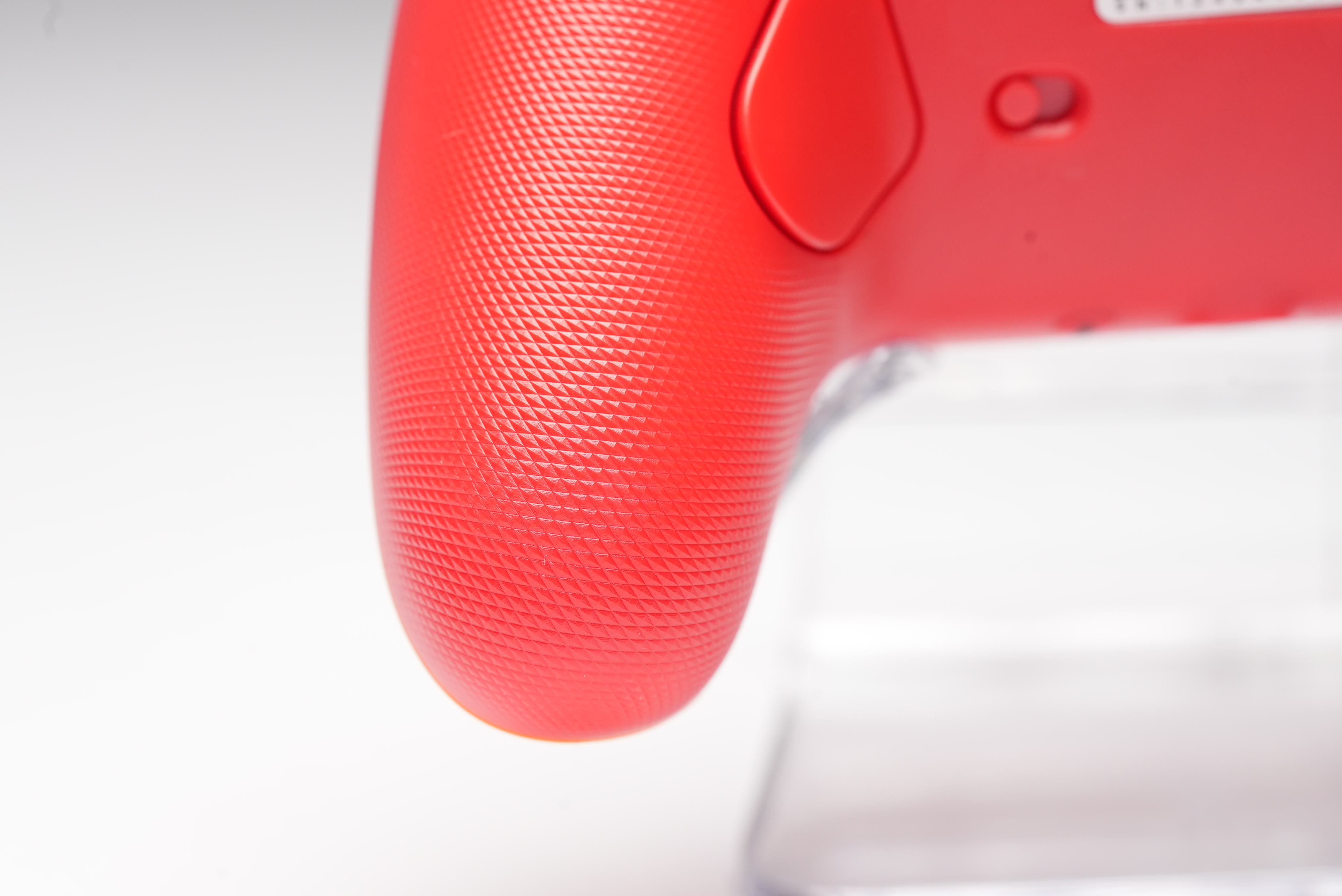 Rote Spielkonsole mit strukturiertem Griff und Knöpfen.