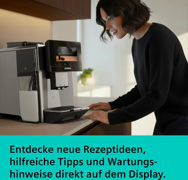 Eine Frau blickt auf einen Kaffeevollautomaten mit Milchkaraffe und Touchscreen.