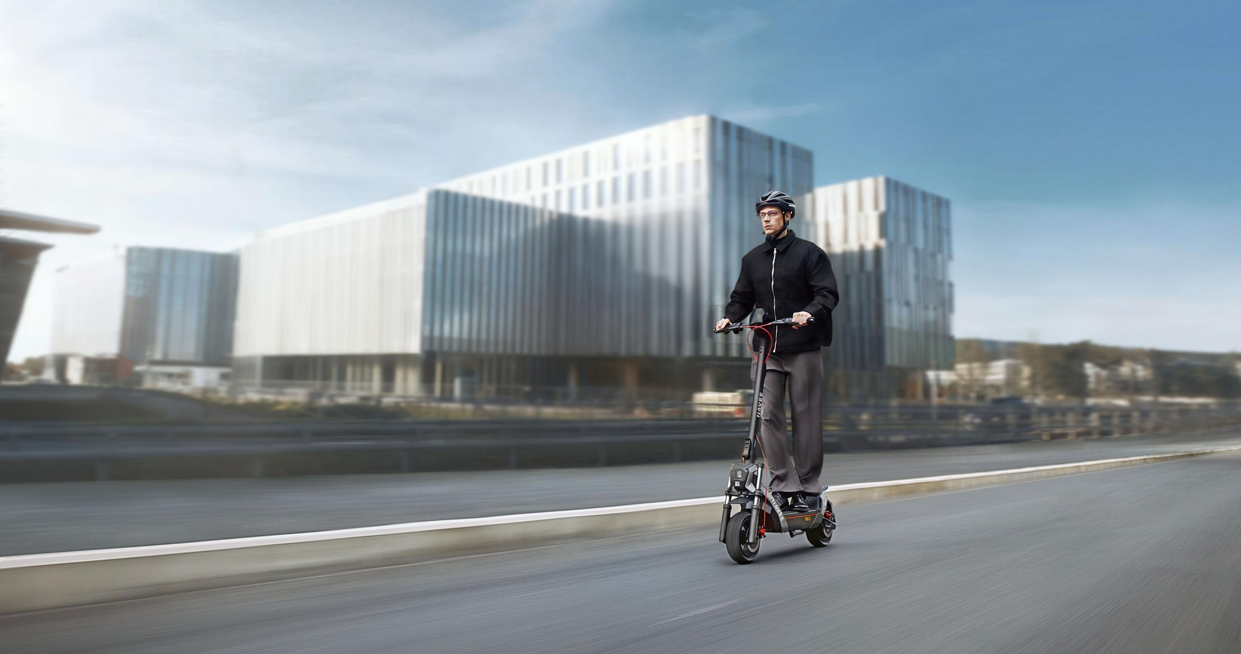 Ein Mann fährt mit einem Elektroroller auf einer Straße vor einem modernen Gebäude.