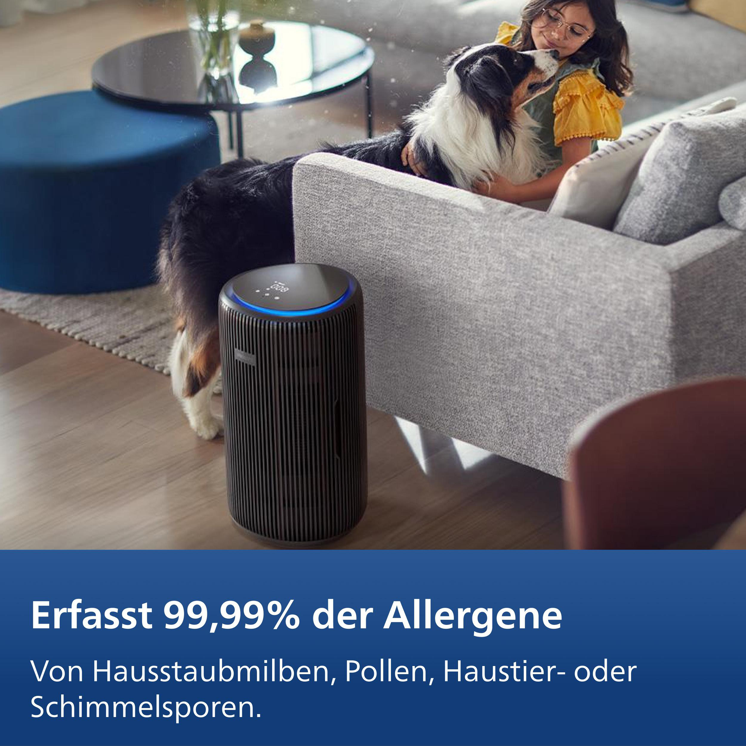 Ein Mädchen streichelt einen Hund vor einem Luftreiniger im Wohnzimmer.