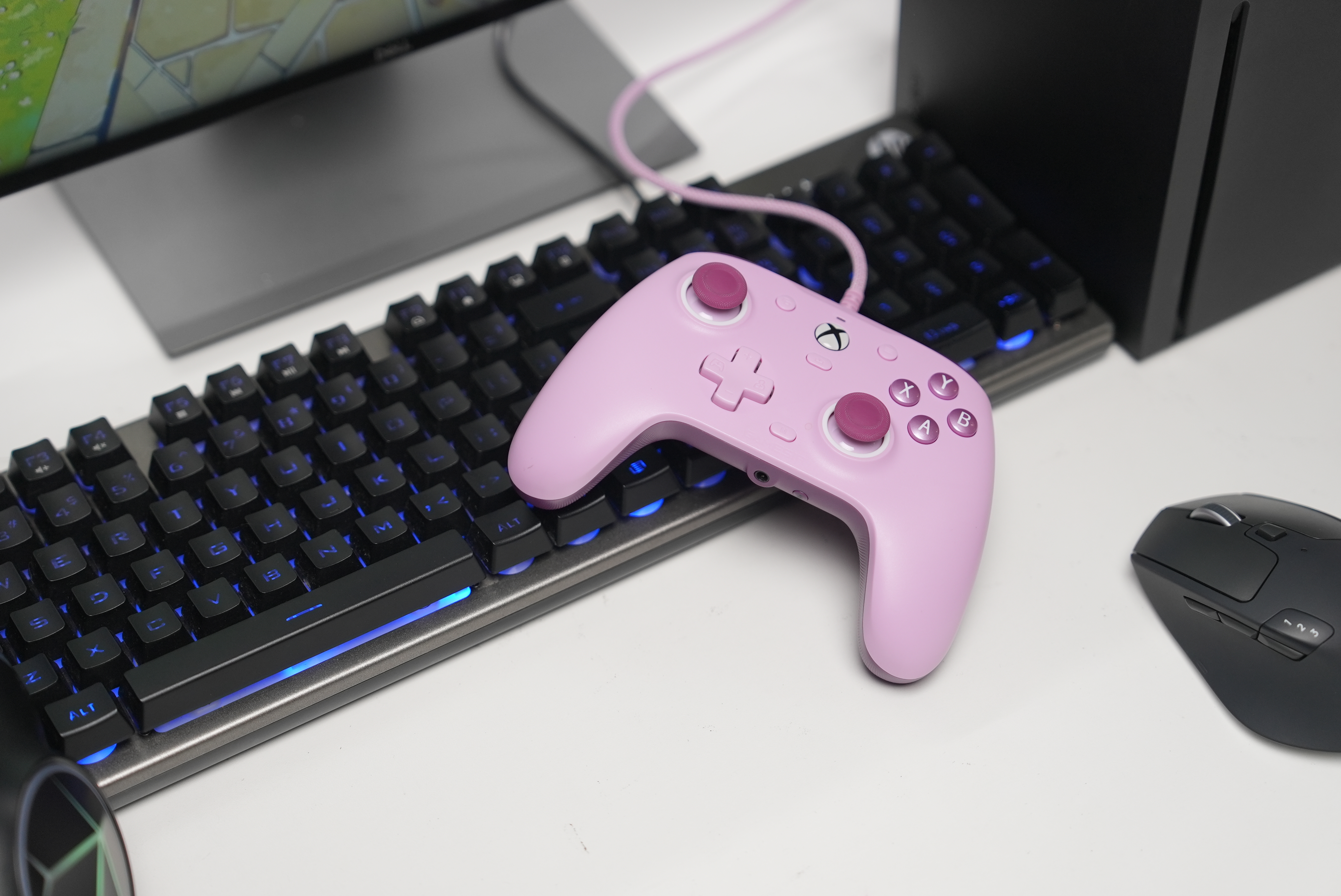 Ein pinker Controller liegt auf einer Tastatur mit blauer Beleuchtung.