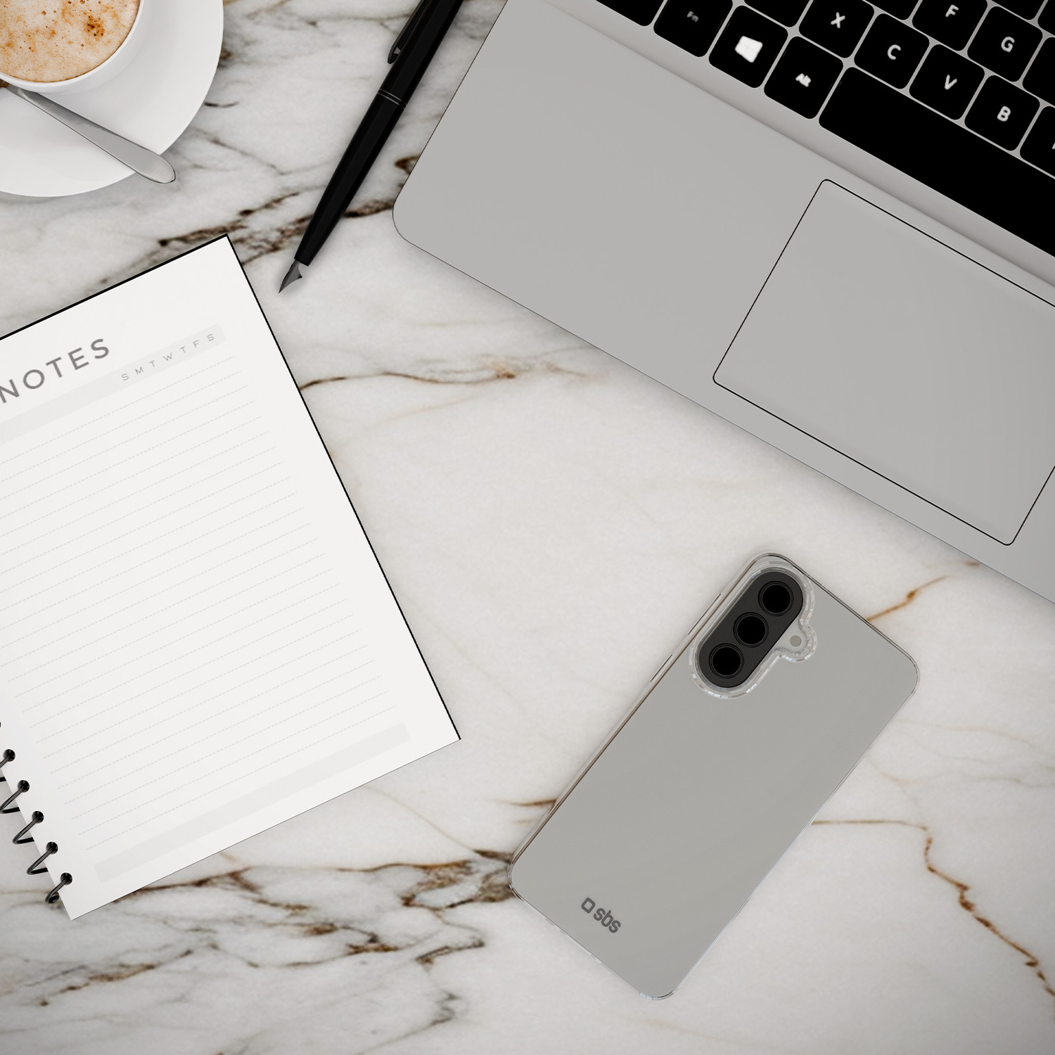 Een laptop, notitieboek, pen, telefoon en koffiekopje op marmer.