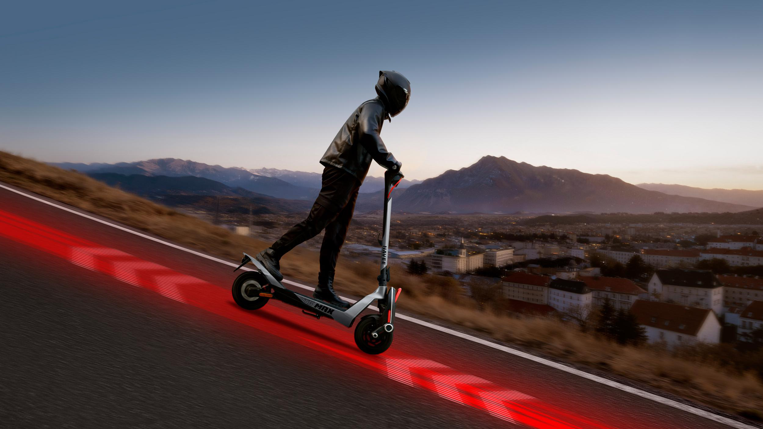 Fahrer auf E-Scooter fährt bergab, rote Lichter auf Straße.