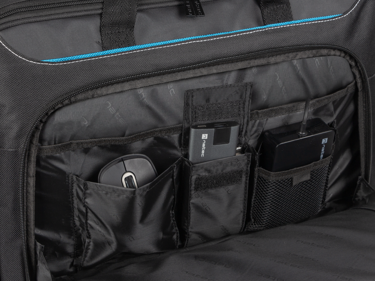 Wnętrze czarnej torby z kieszeniami na mysz, power bank i adapter.