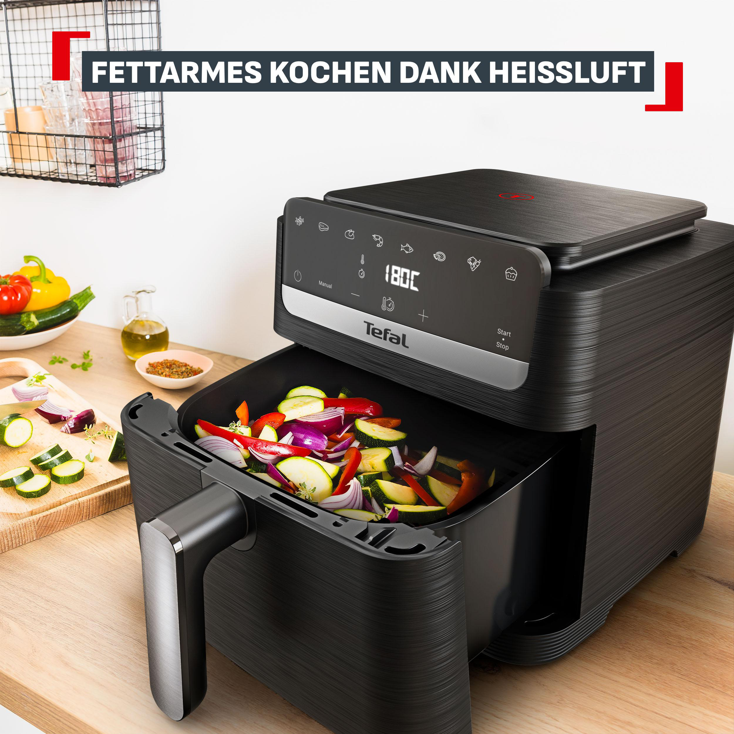 Schwarze Heißluftfritteuse mit Gemüse gefüllt, auf einem Holztisch.