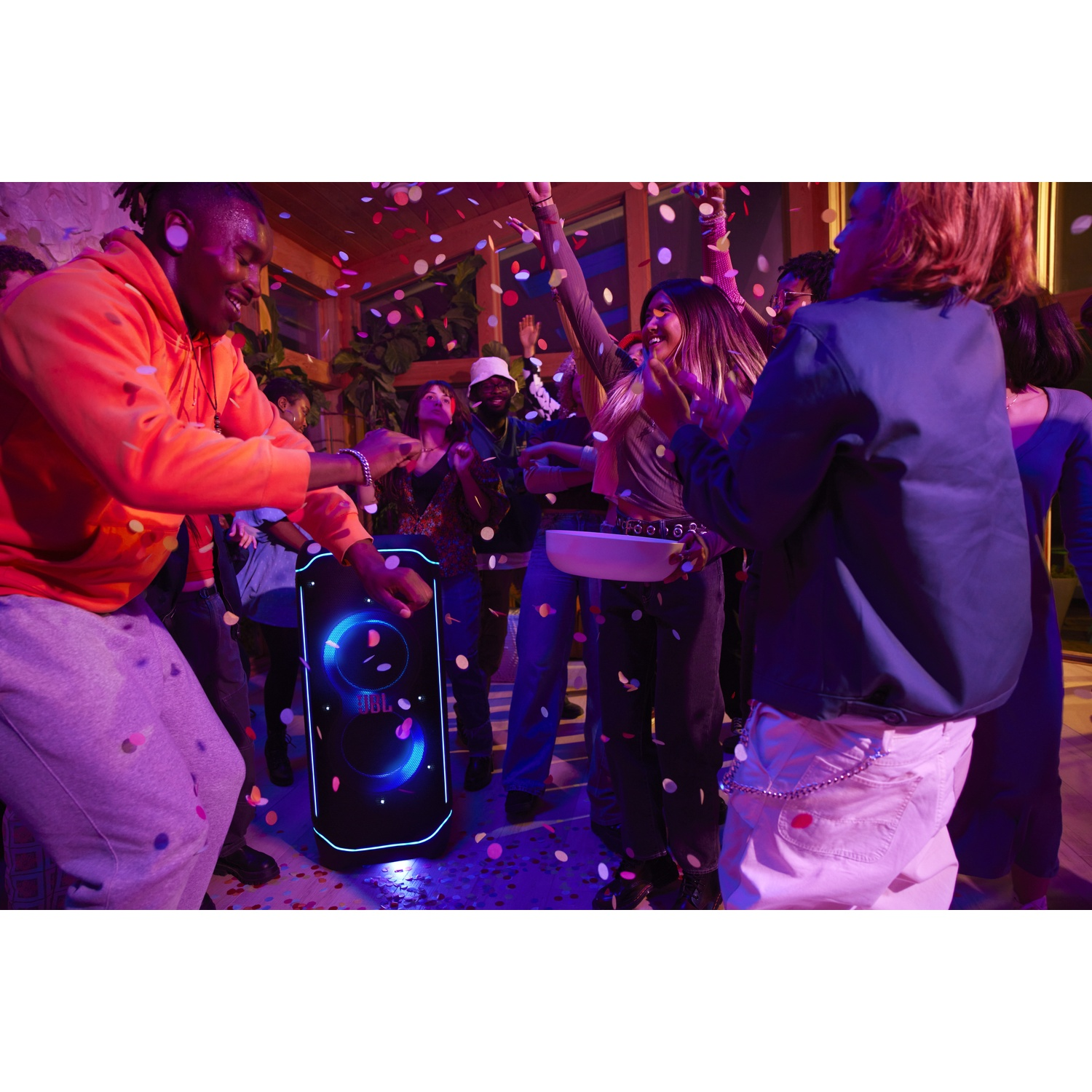 People dance at a party with confetti falling around a large JBL speaker.