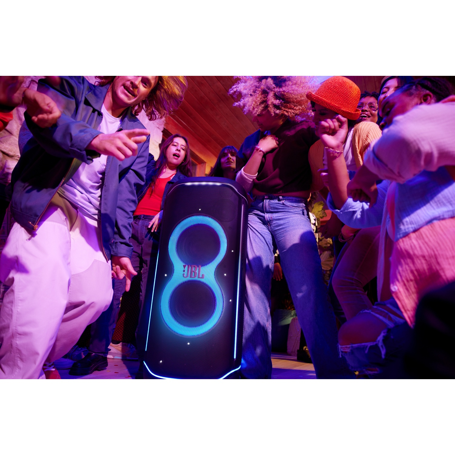 People dance to a JBL speaker with blue lights.