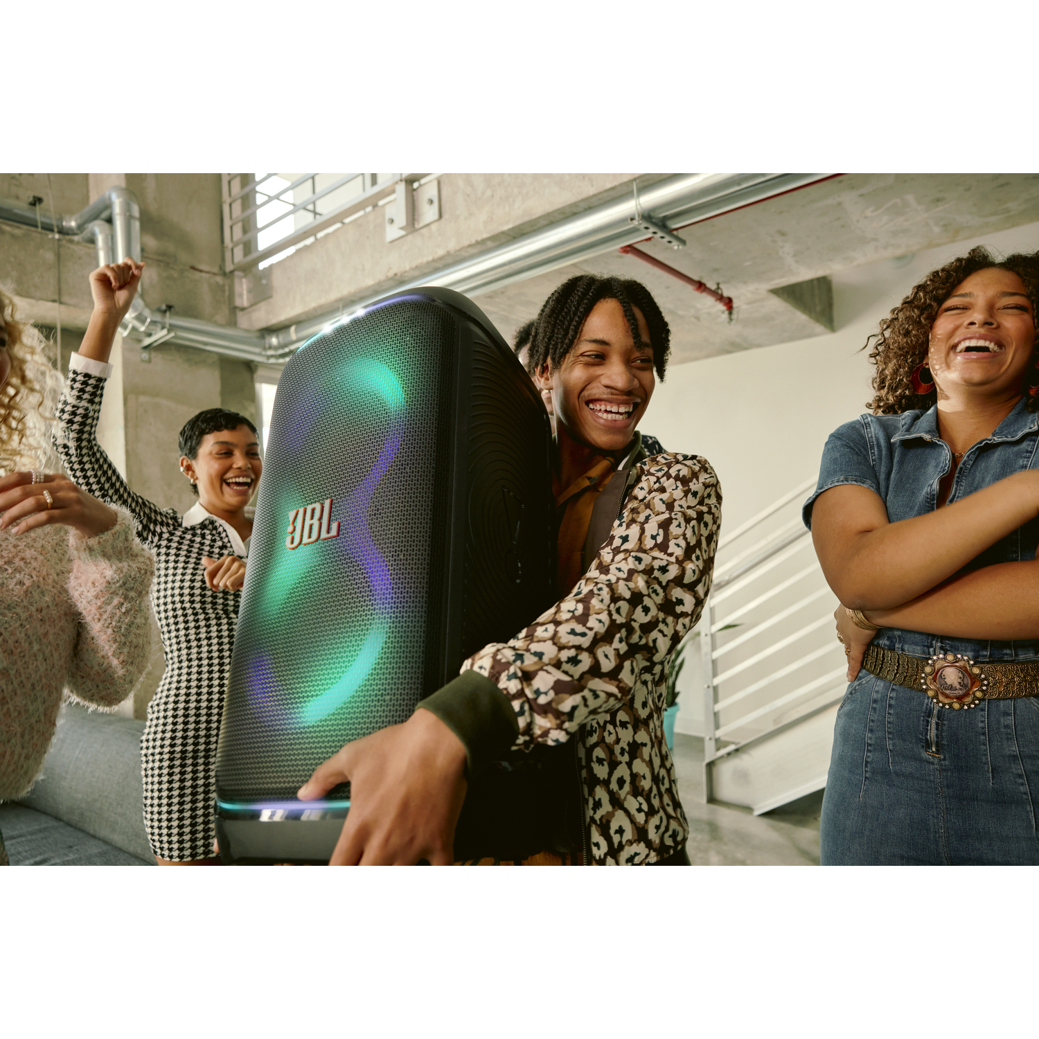 Een groep vrienden viert feest met een JBL-speaker die kleurrijke lichten uitstraalt.