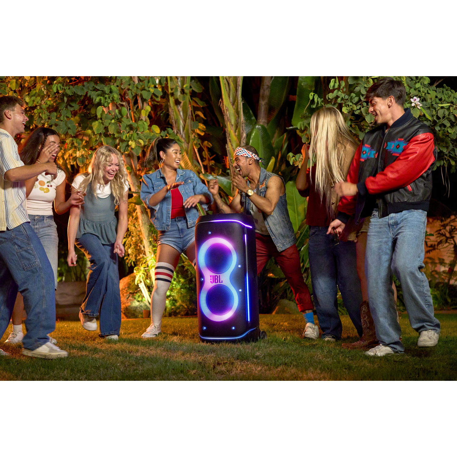 Een groep jongeren danst 's nachts buiten rond een JBL speaker.